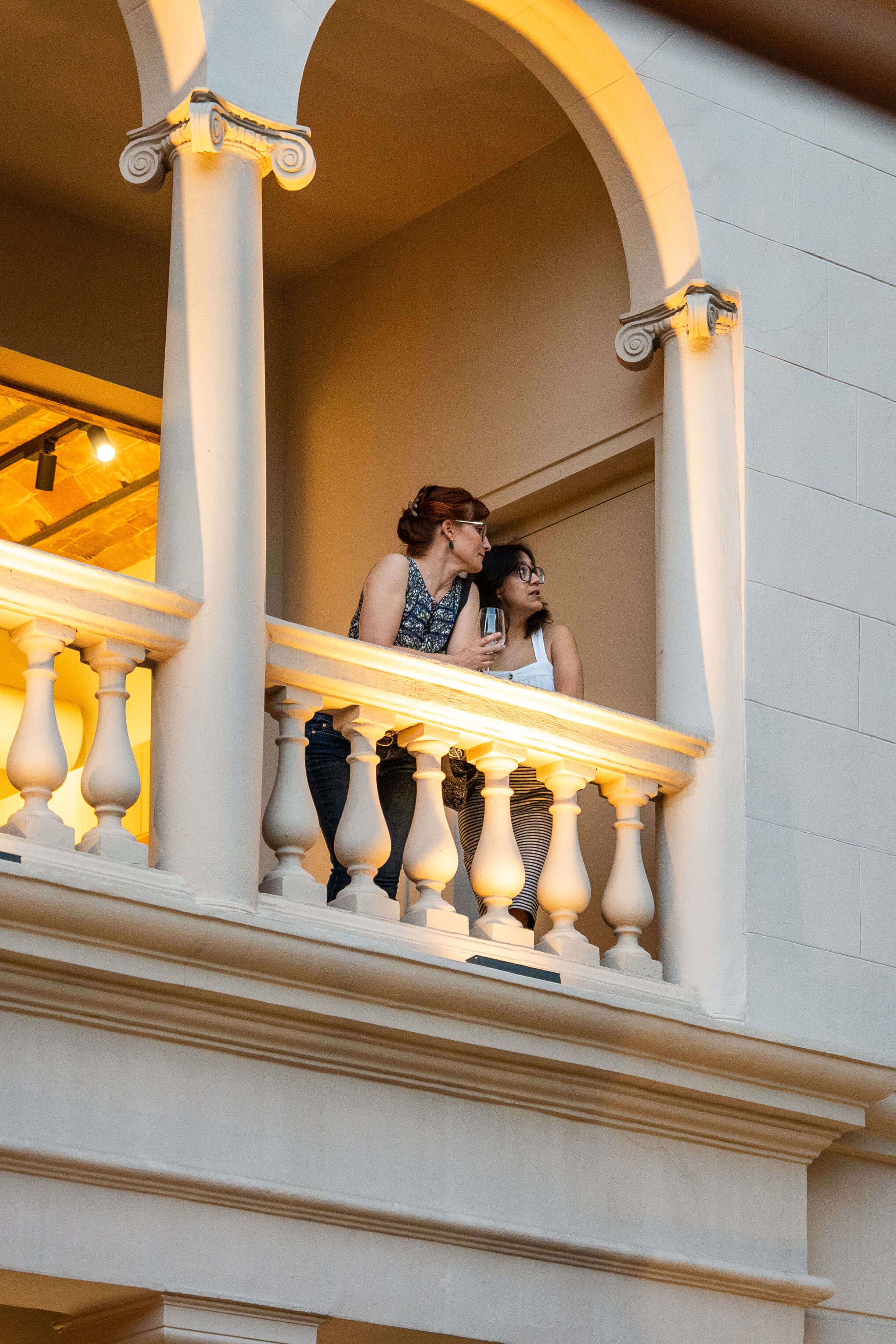 Dos personas conversando en el balcón de un edificio histórico