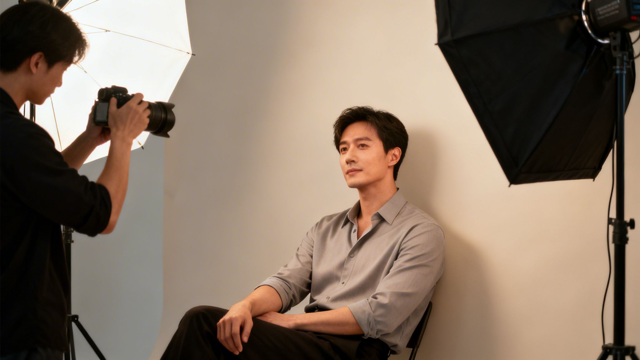 Ein Fotograf macht ein Porträtfoto eines eleganten Mannes im professionellen Fotostudio mit Beleuchtung.