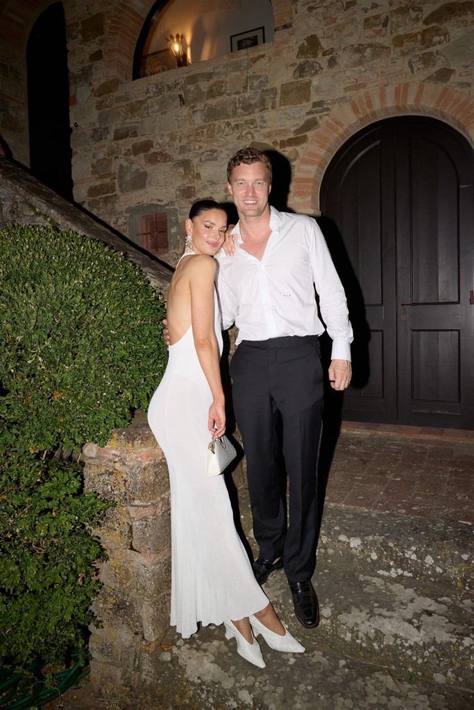 Flash portrait of bride leaning against staircase while groom is leaning agains her