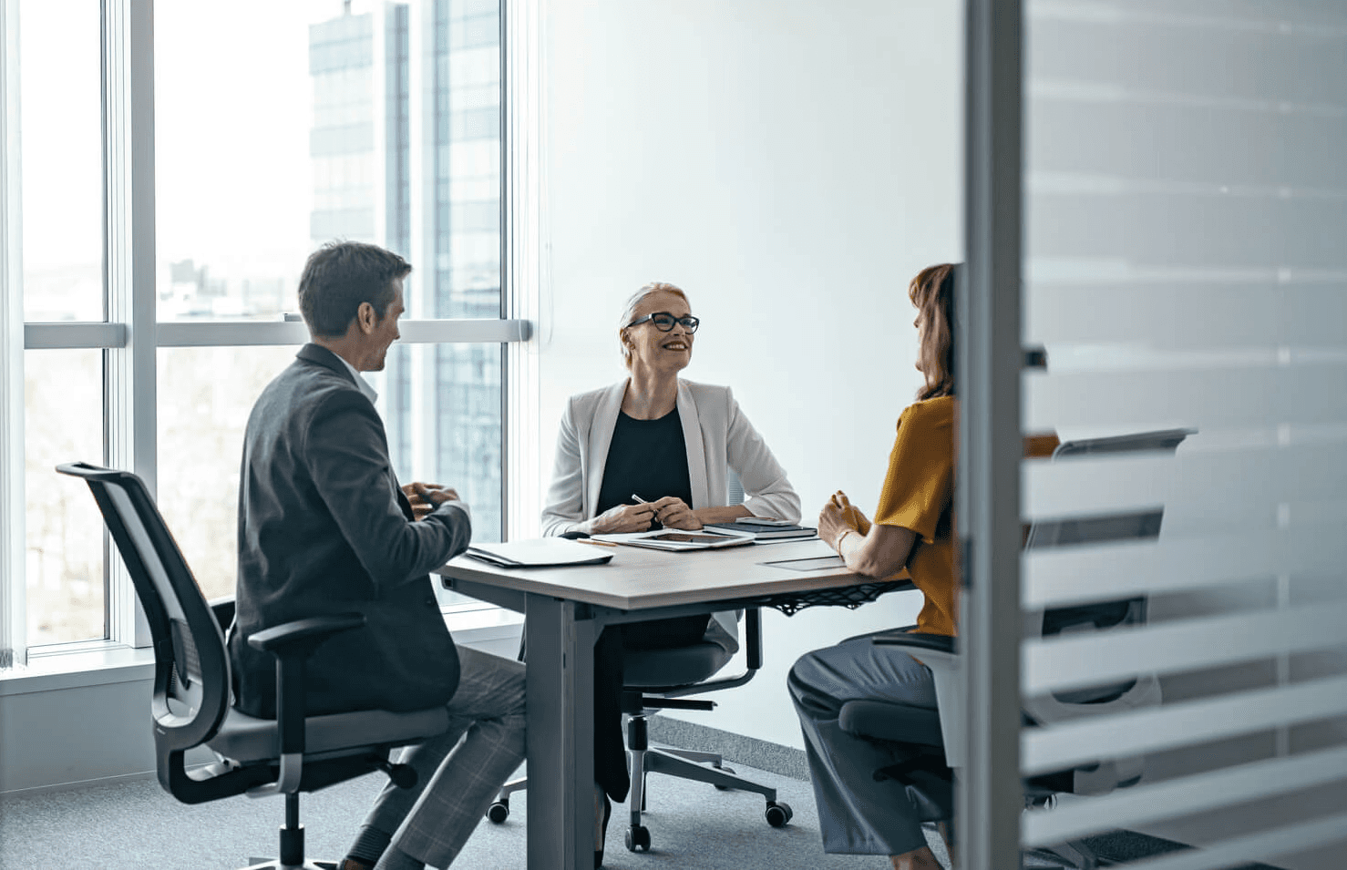 Three business partners in professional attire engaged in a productive meeting in an office.