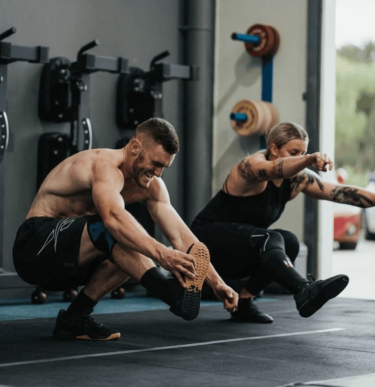 A male and female pair doing pistol squats at a gym