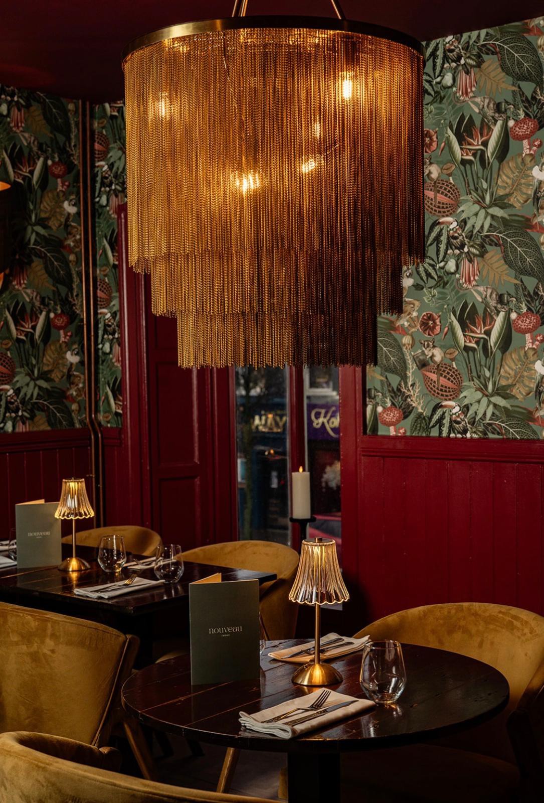Plate with a seared salmon fillet topped with green herb garnish and sauce, served on a white dish placed on a dark green marble table beside a white candlestick.