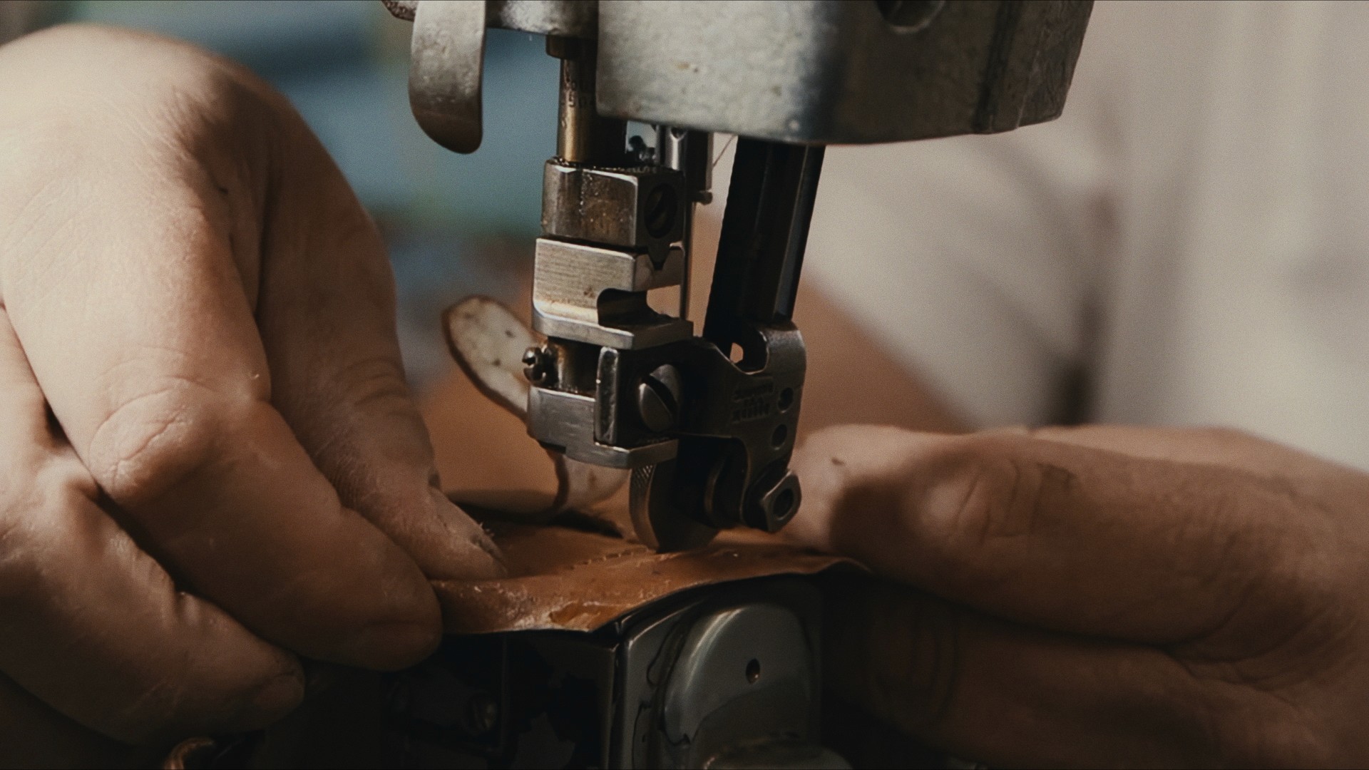 Hands guiding leather through a sewing machine, Maddman