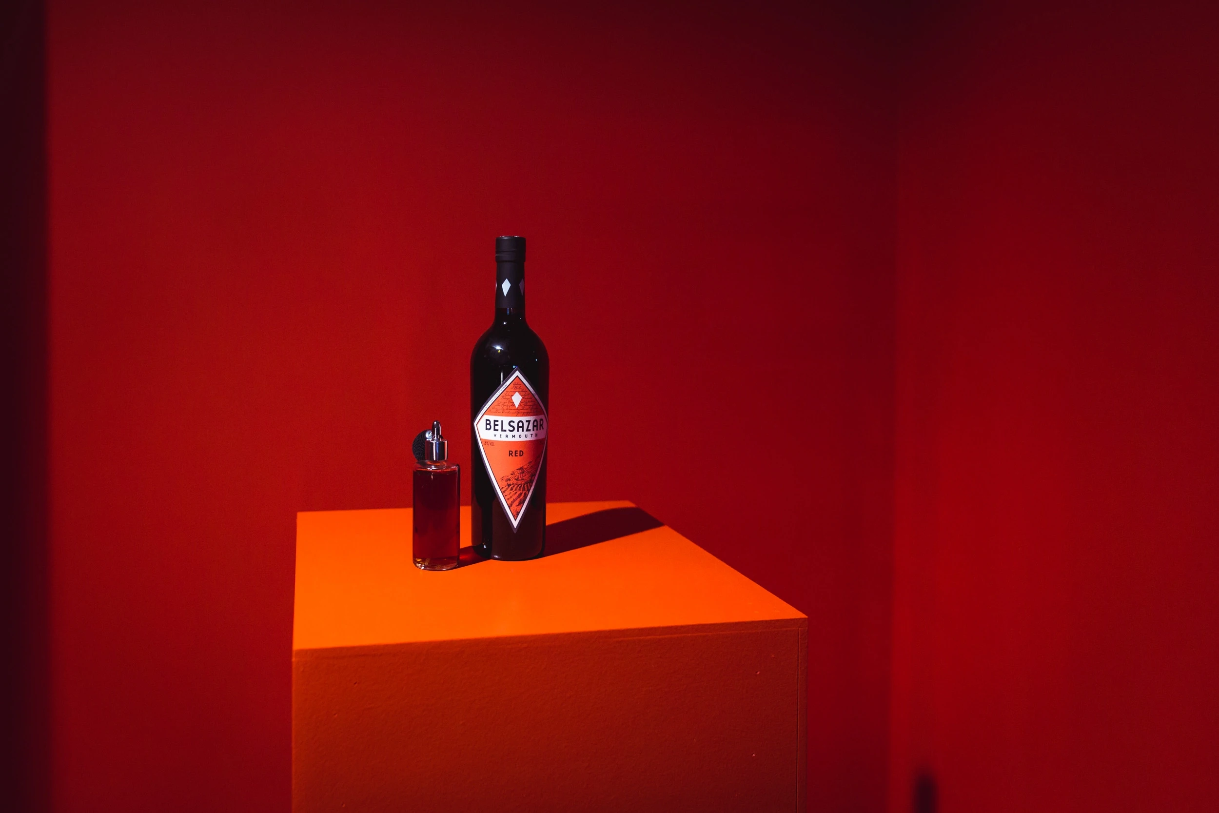 Belsazar bottle and a small filled glass bottle on an orange pedestal in a deep red room at DIAGEO BCB18.