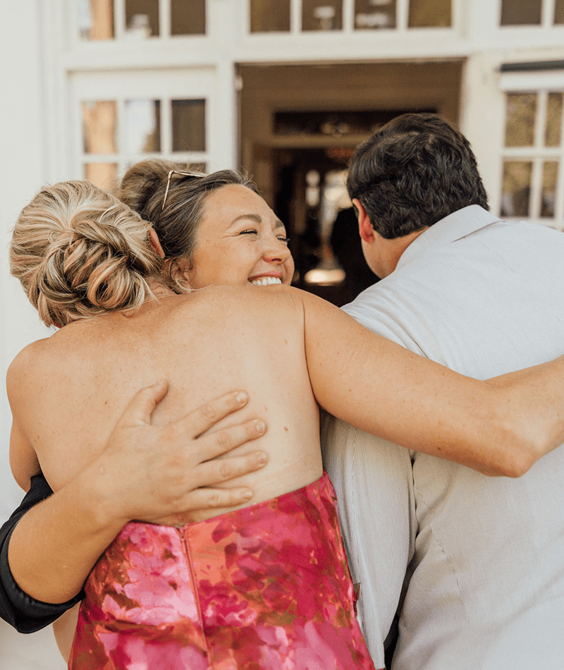 Father and mother of the bride hugging wedding planner at Berry College in Georgia