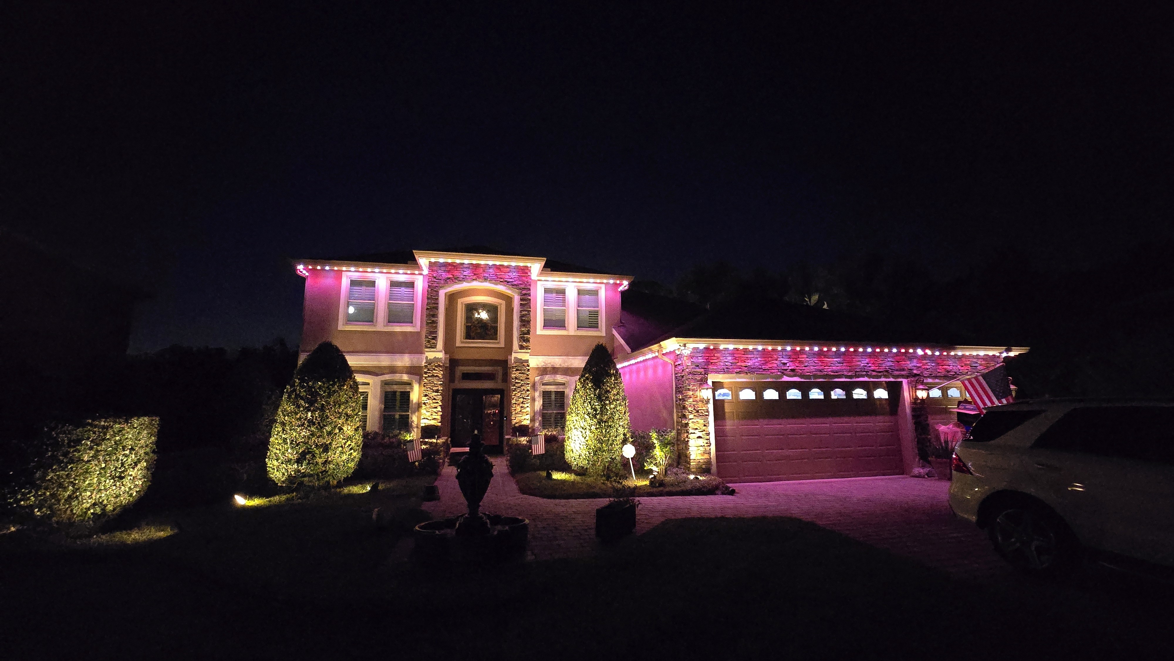 Permanent roofline LED lighting installed on home exterior with color-changing effects Pink