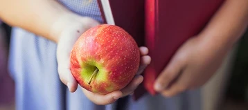 Enfant tenant une pomme dans sa main.