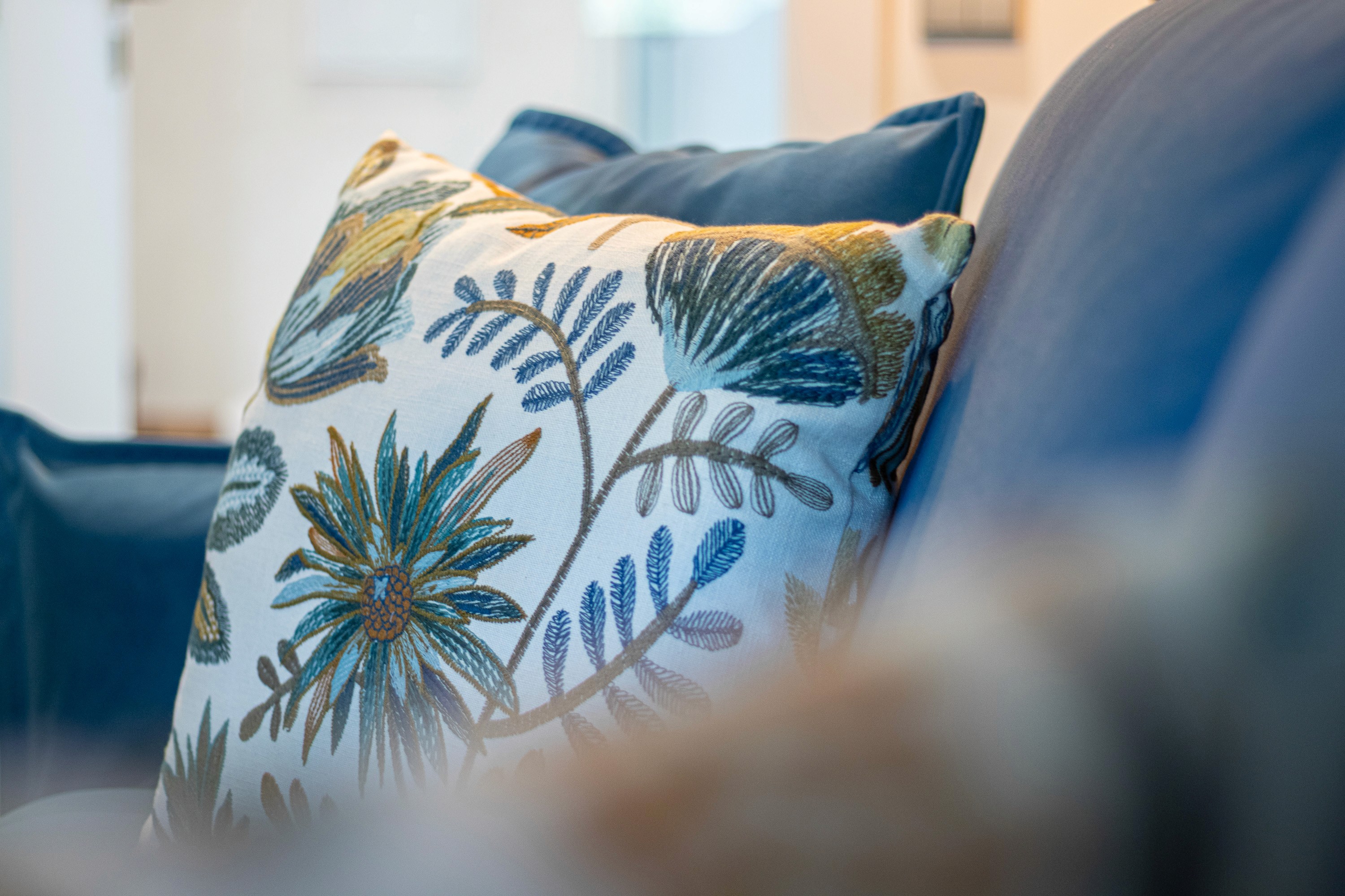 An embroidered botanical cushion on the blue sofa bed