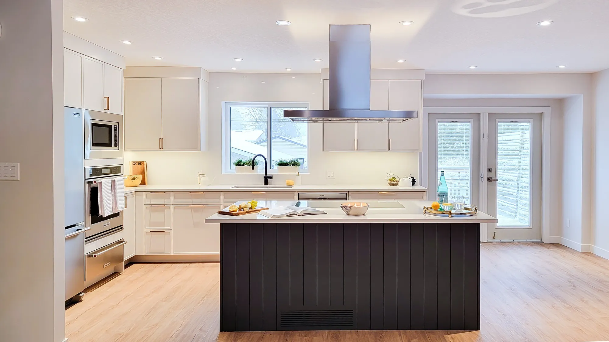 Image of kitchen with blue island and stainless steel hood fan dropped from the ceiling.