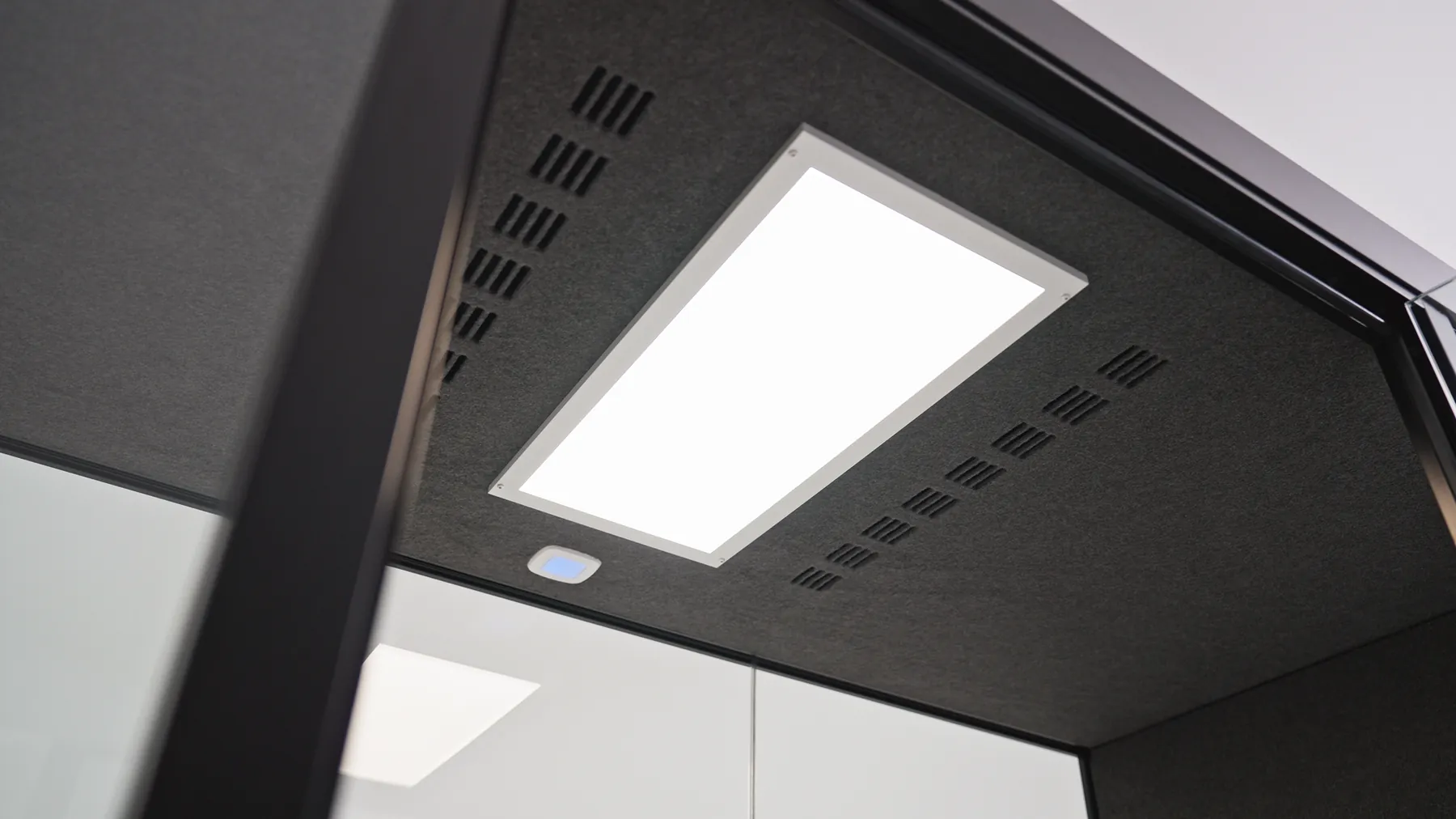 Underside of a Silen pod ceiling showing an LED light panel and ventilation slats