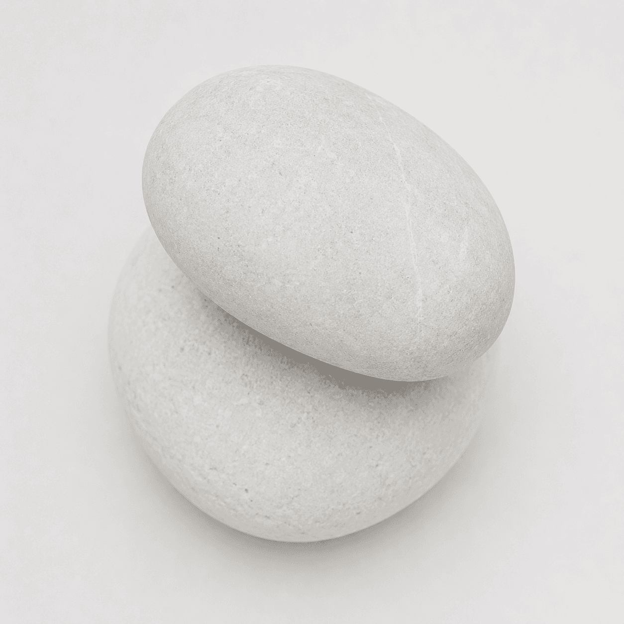 Two stones balanced on white surface representing the precarious but achievable equilibrium of weight maintenance