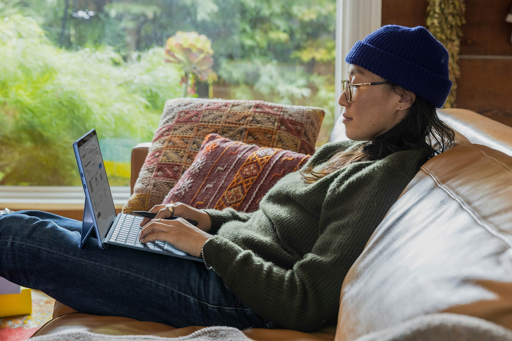 A woman sitting on a couch with a laptop, working comfortably from home.