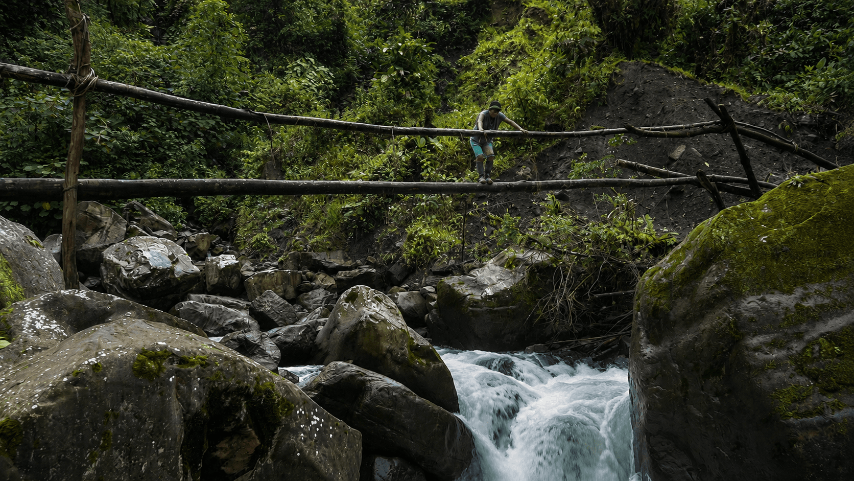 Person crossing a wooden bridge over a mountain river in U’wa territory.