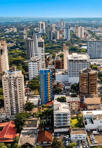 Vista aérea da cidade com edifícios residenciais e comerciais cercados por áreas verdes urbanas