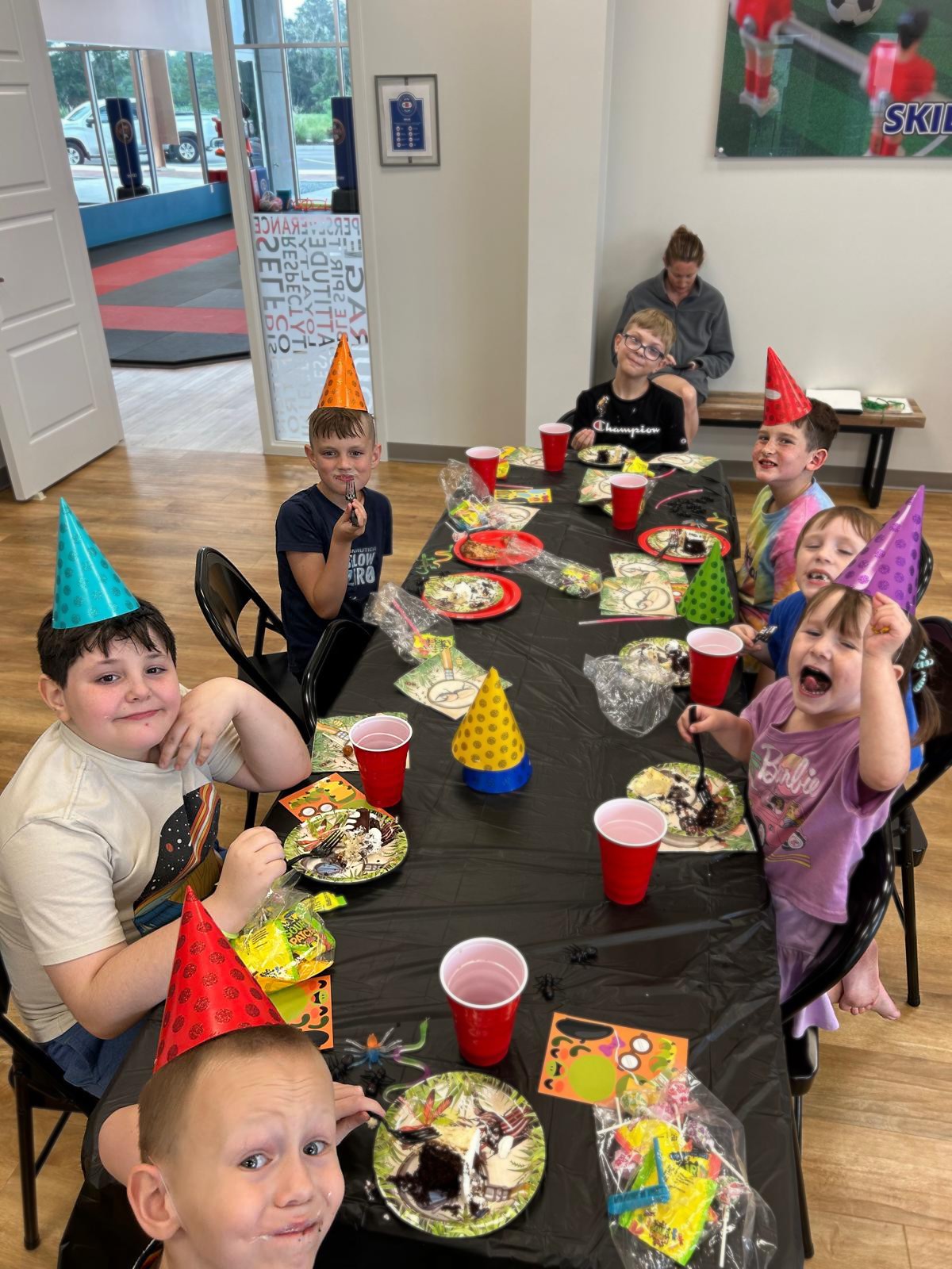 Kids smiling at camera while eating birthday cake.