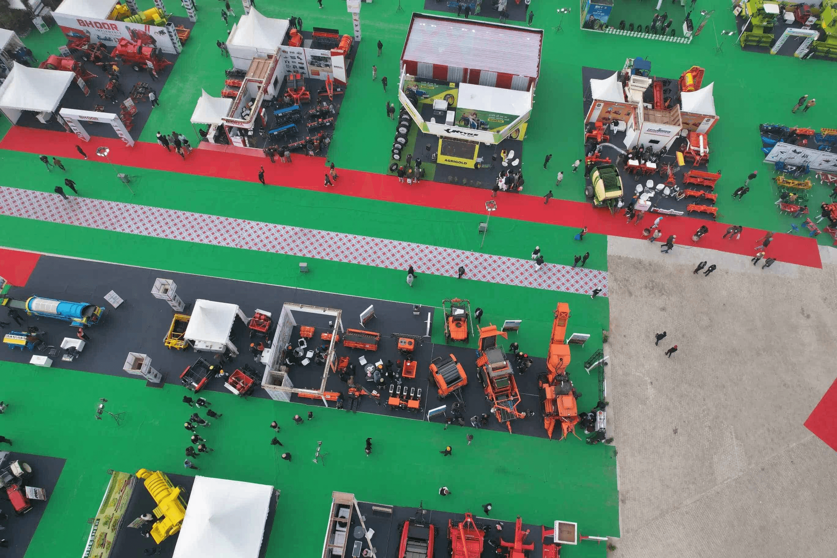  Overhead view of Kothi Meena Bazar Ground in Shahganj, Agra, a spacious open exhibition venue on M.G. Road 2 surrounded by urban streets and trees, set up with expo tents, banners, and parking areas for Agri Agro Grand Expo 2026 visitors and exhibitors. ​
