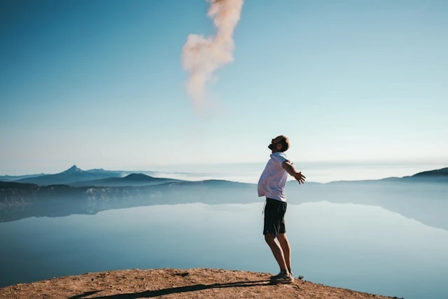 Person standing on a mountain at sunrise with arms open wide, symbolizing structure, resilience, and mental clarity.