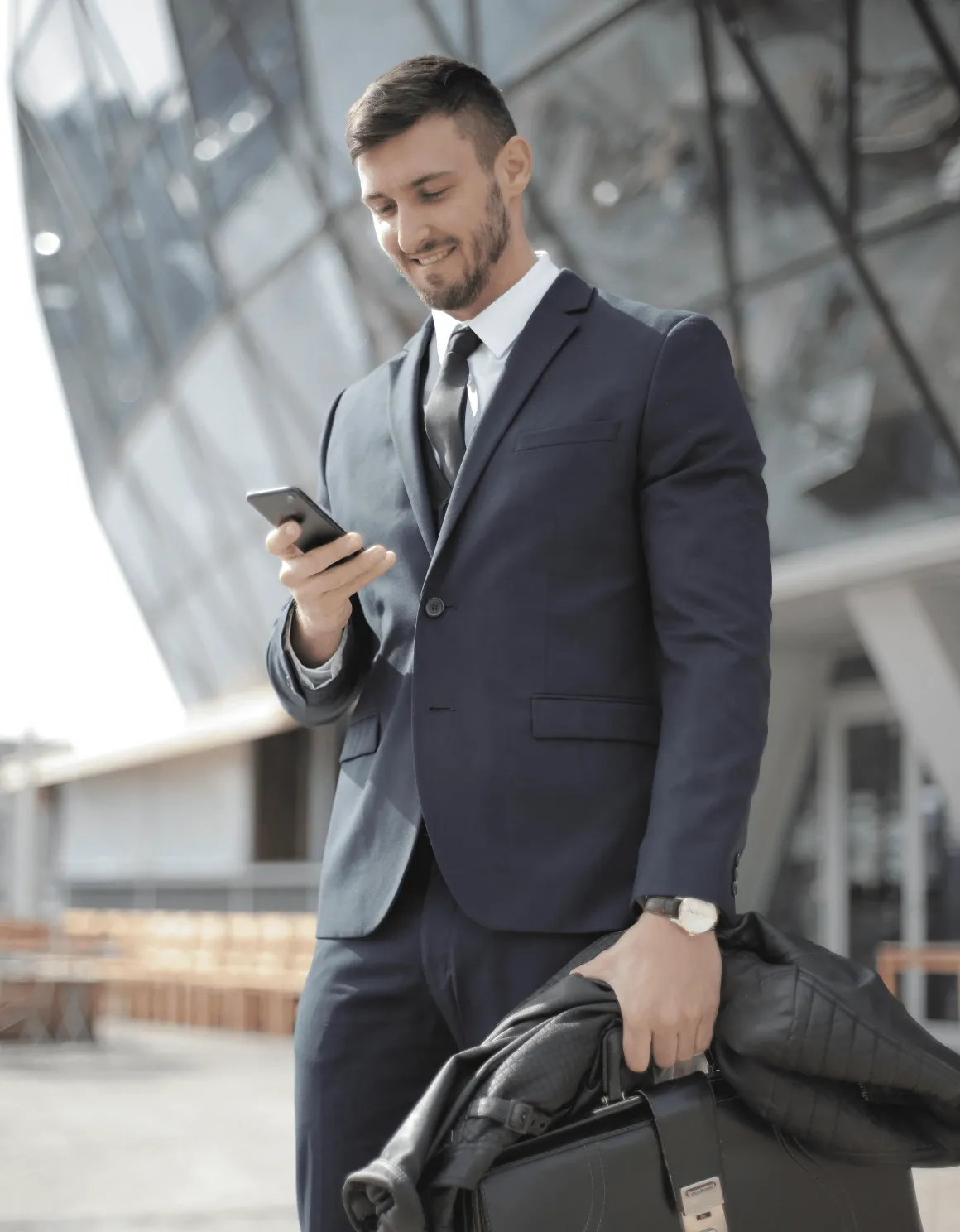 a-confident-businessman-in-a-suit-smiles-while-texting-outside-a-modern-building - andrea-piacquadio (pexels)