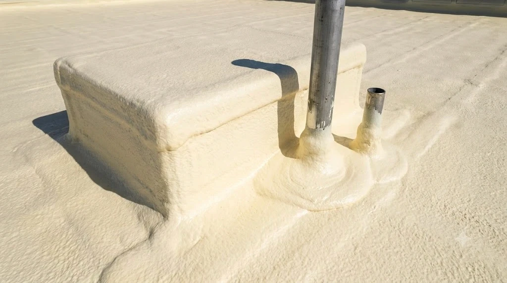 Seamless spray foam roofing self-flashing around rooftop HVAC curbs and pipe penetrations