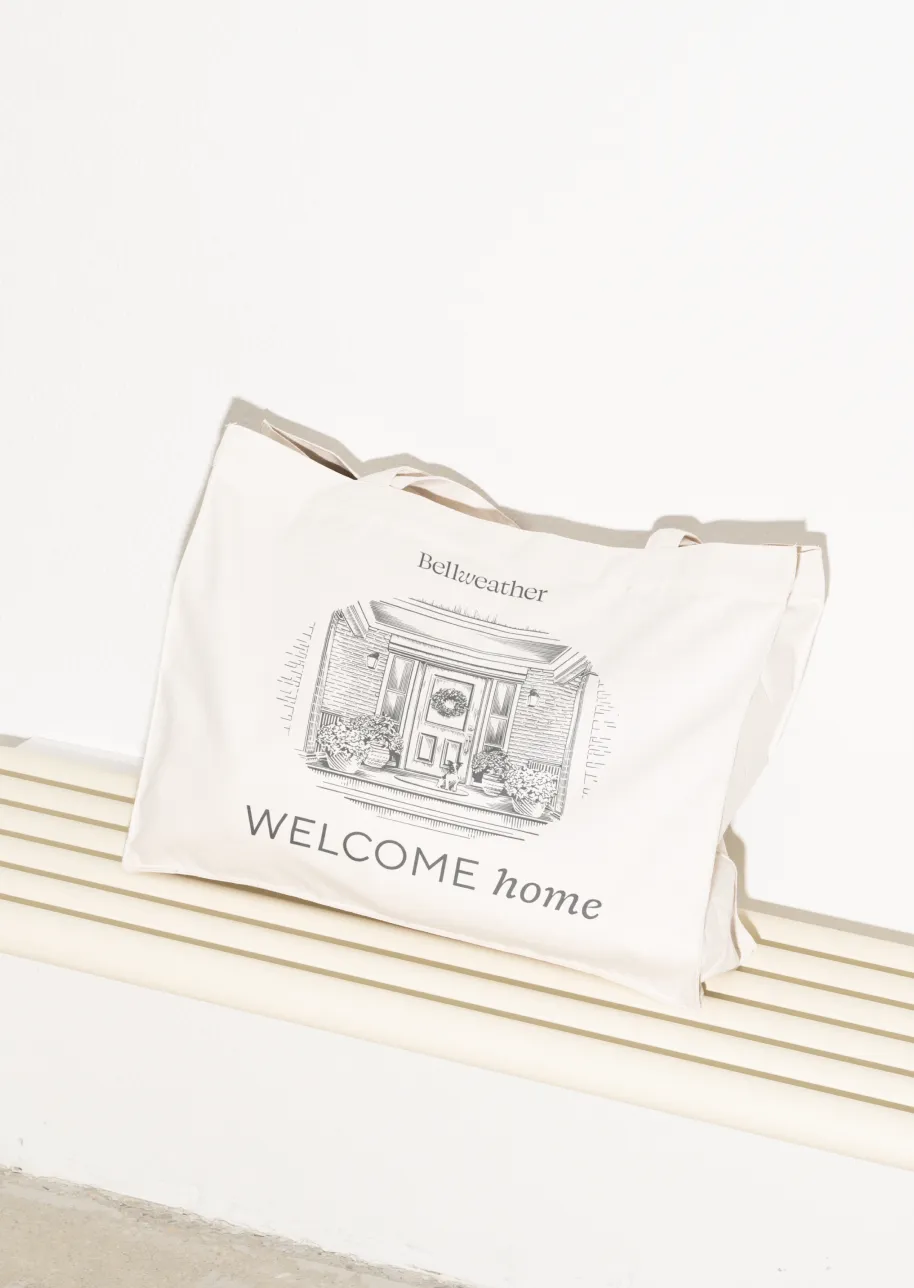 Beige Bellweather tote bag with "Welcome home" and house illustration.