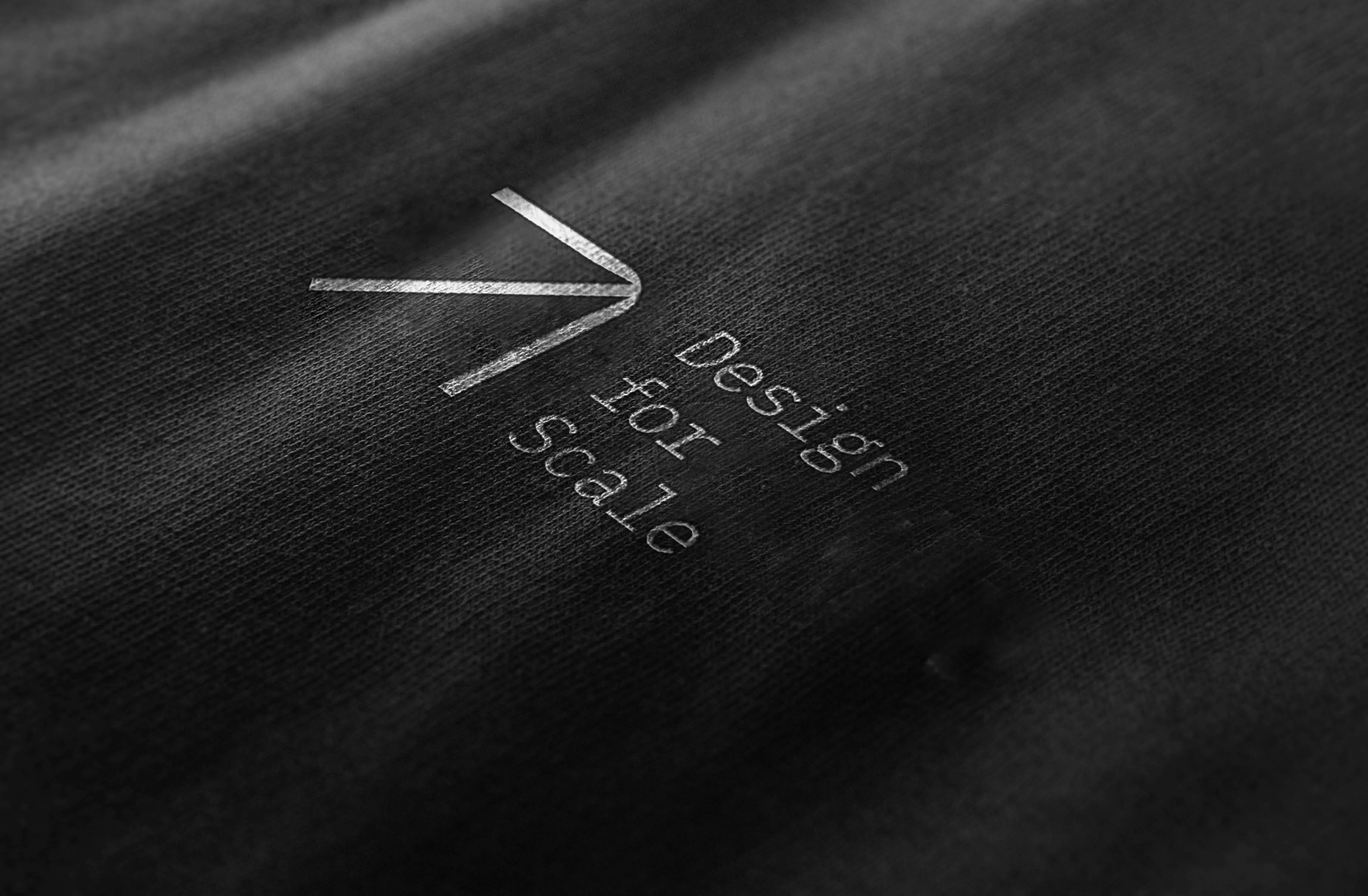 Stylish close-up of a shirt featuring "Design for Scale" printed on black fabric.