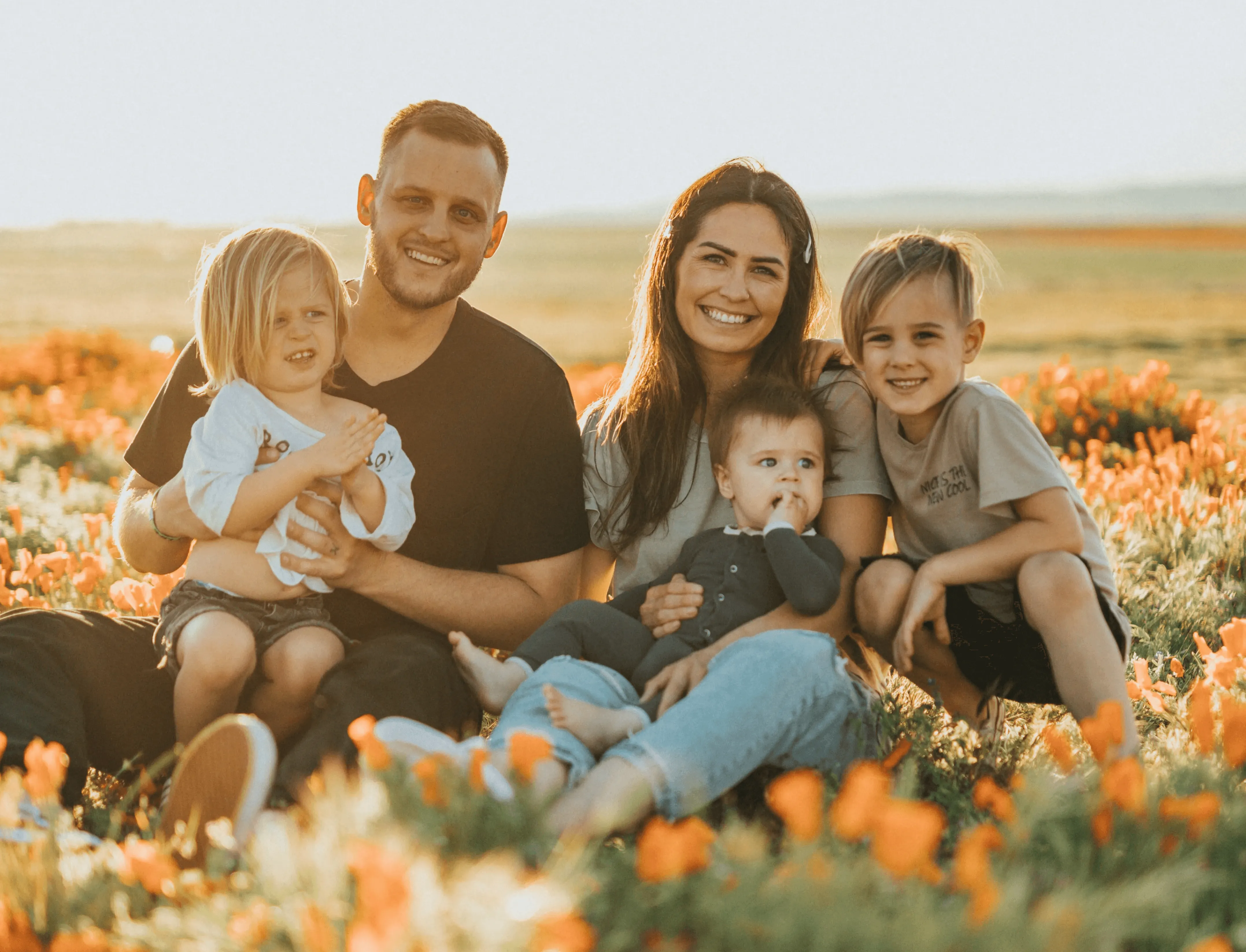 3 women and 2 men sitting on green grass field during daytime