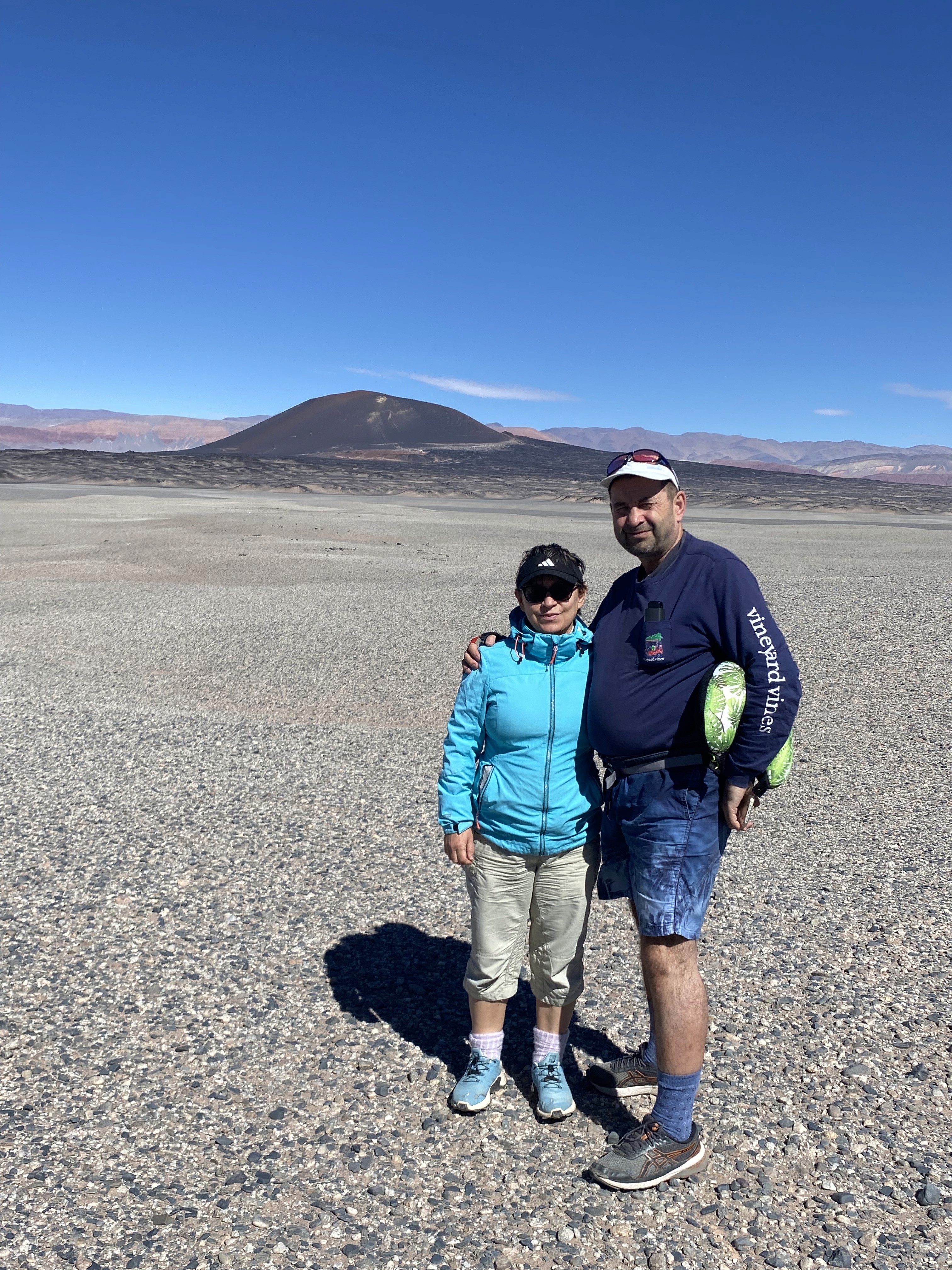 Mujer sentada sobre un tronco frente a una cascada doble en un bosque frondoso de Argentina.