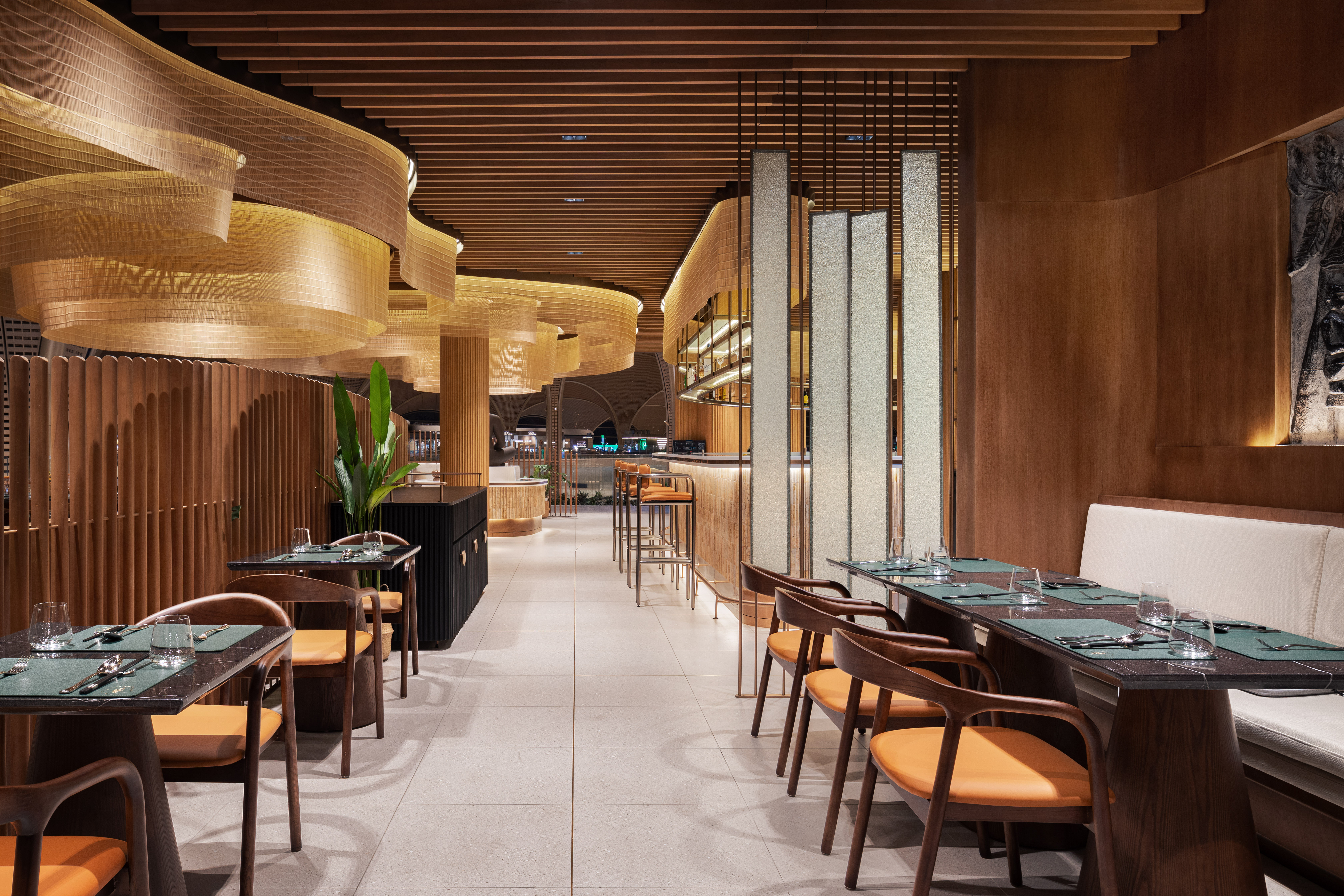 luxury-airport-bar-malis-restaurant Modern bar area at Malis Restaurant featuring brushed bronze accents and a central Buddha sculpture.