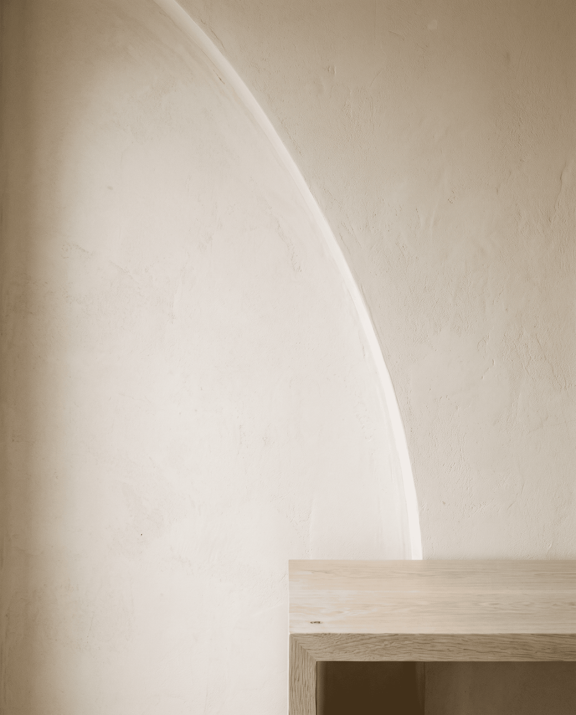 A warm limewash plaster wall with a soft curved shadow