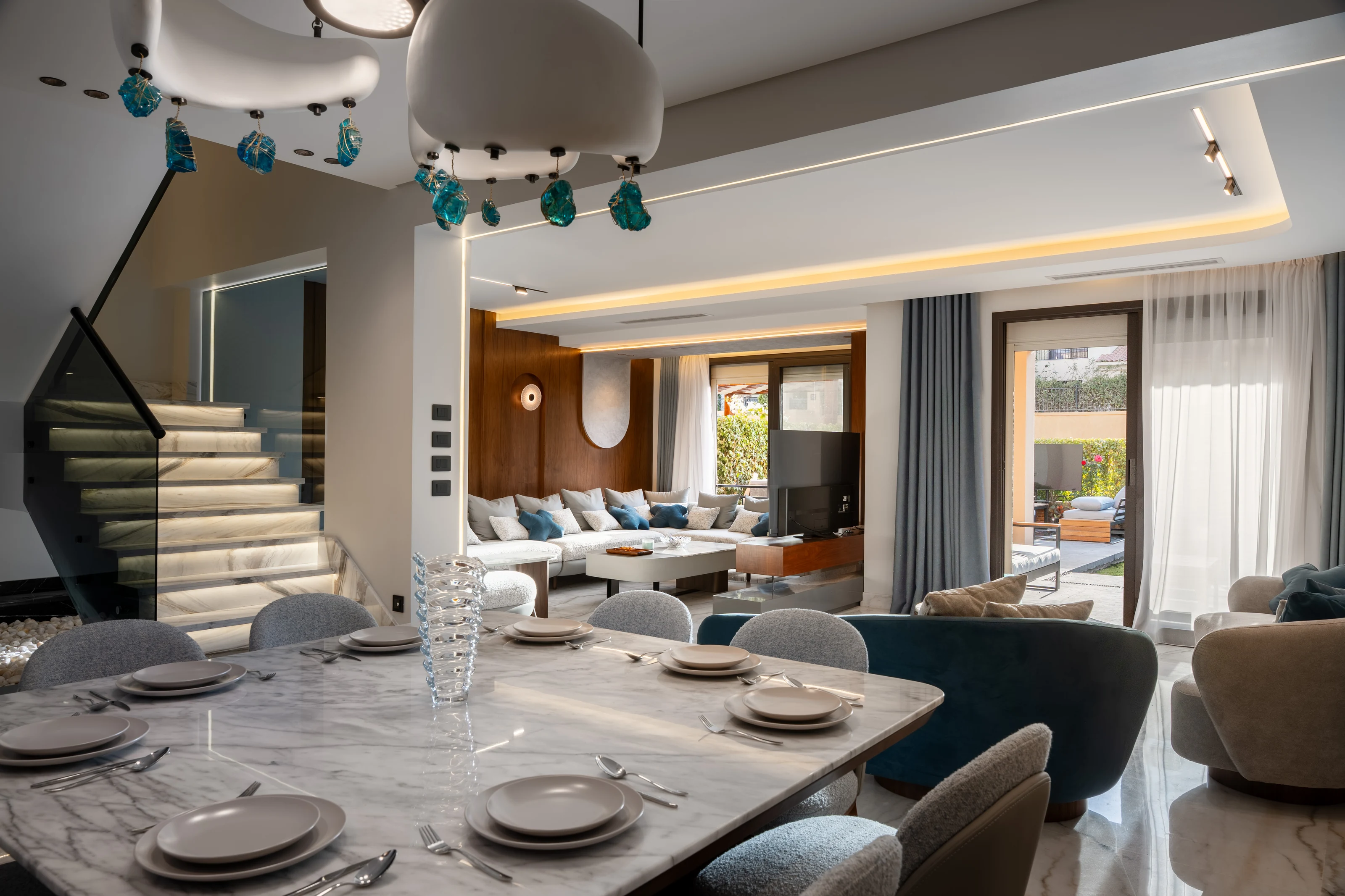 Open dining and living spaces inside Mivida Twin Villa with marble flooring and sculptural lighting.