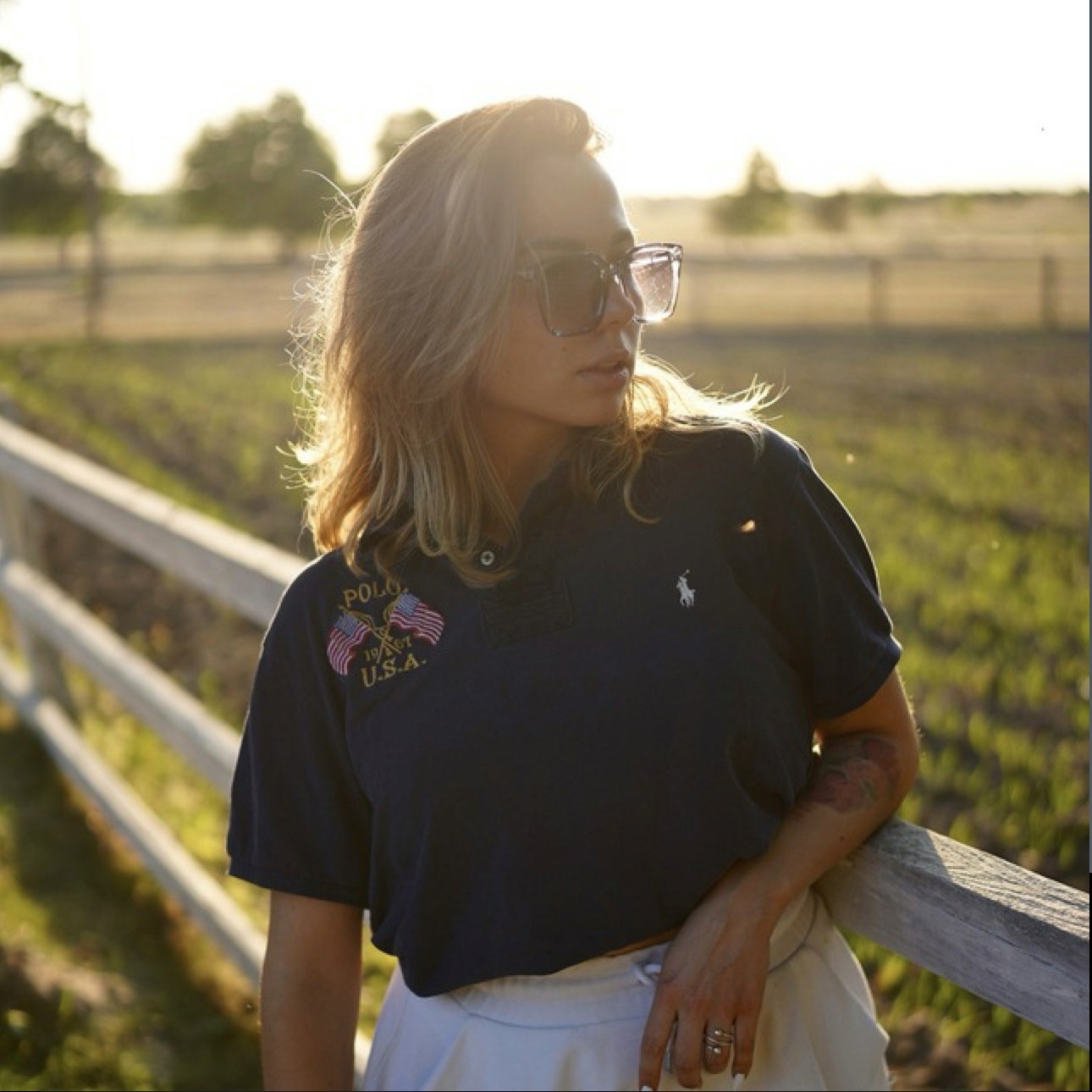 Black-and-white portrait of a man with an afro in motion, wearing a hoop earring and chain necklace, against a light gray background.
