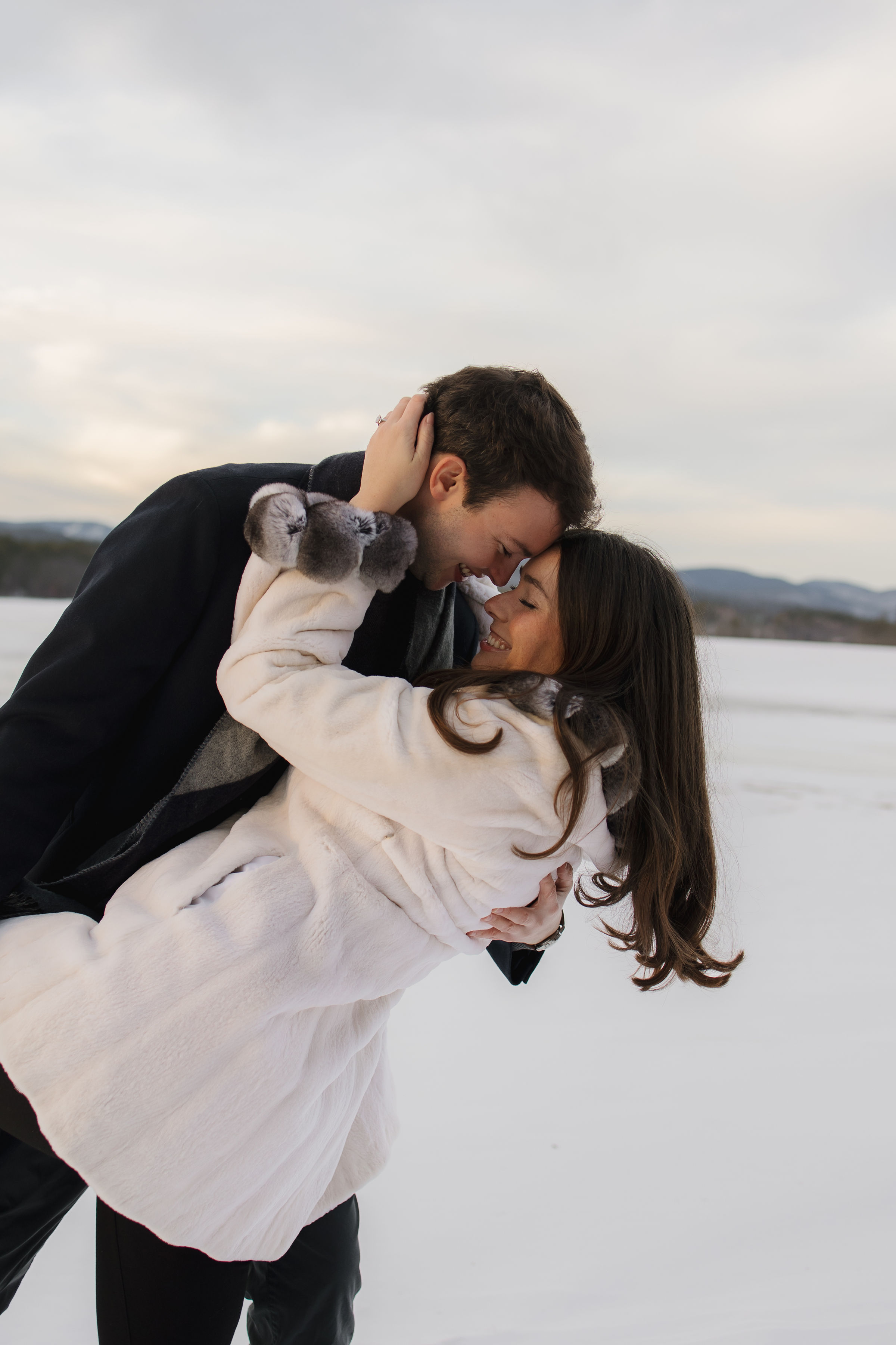 A couple embraces lovingly on a wooden dock.