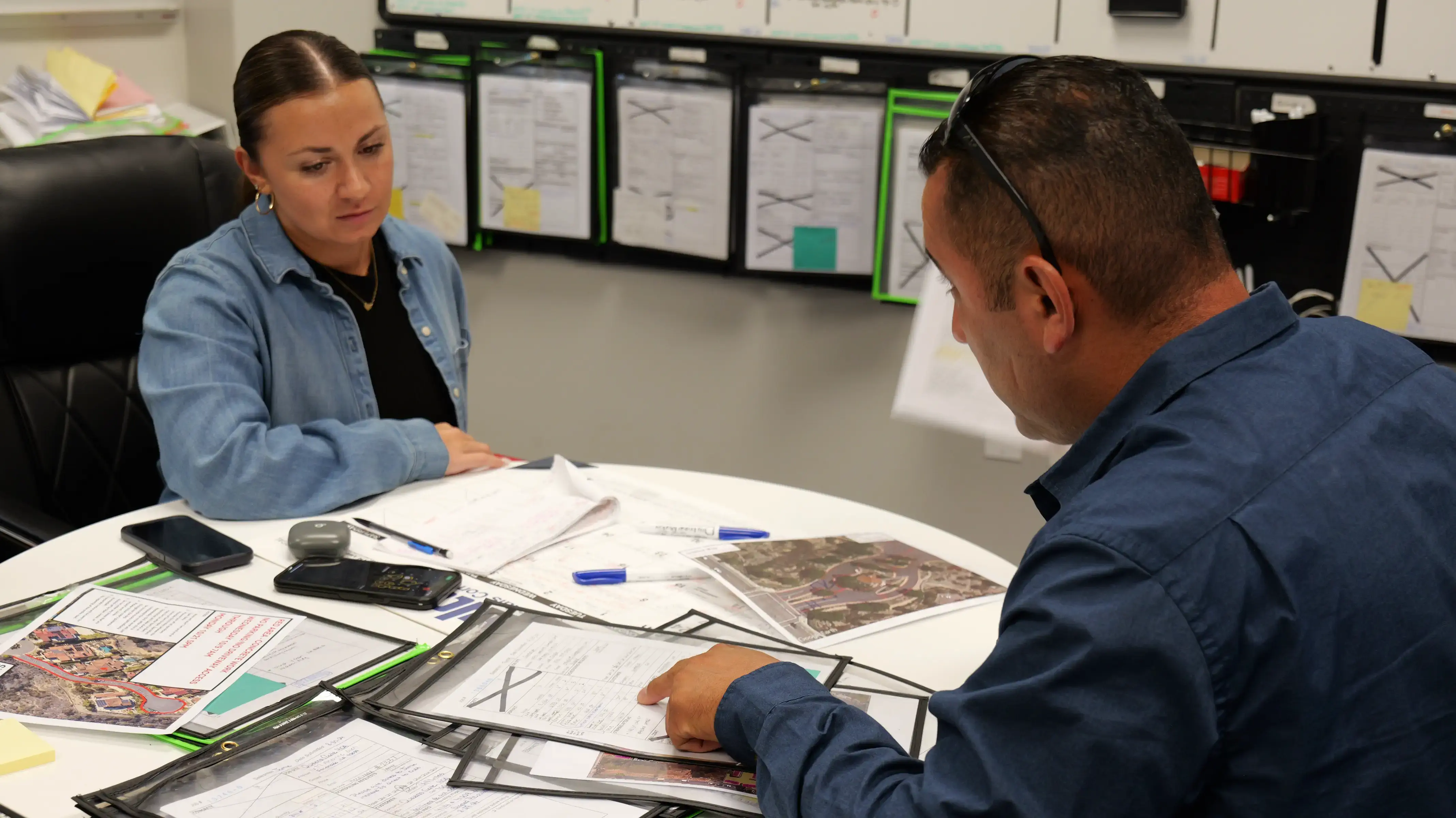 Two office employees discussing project paperwork on table