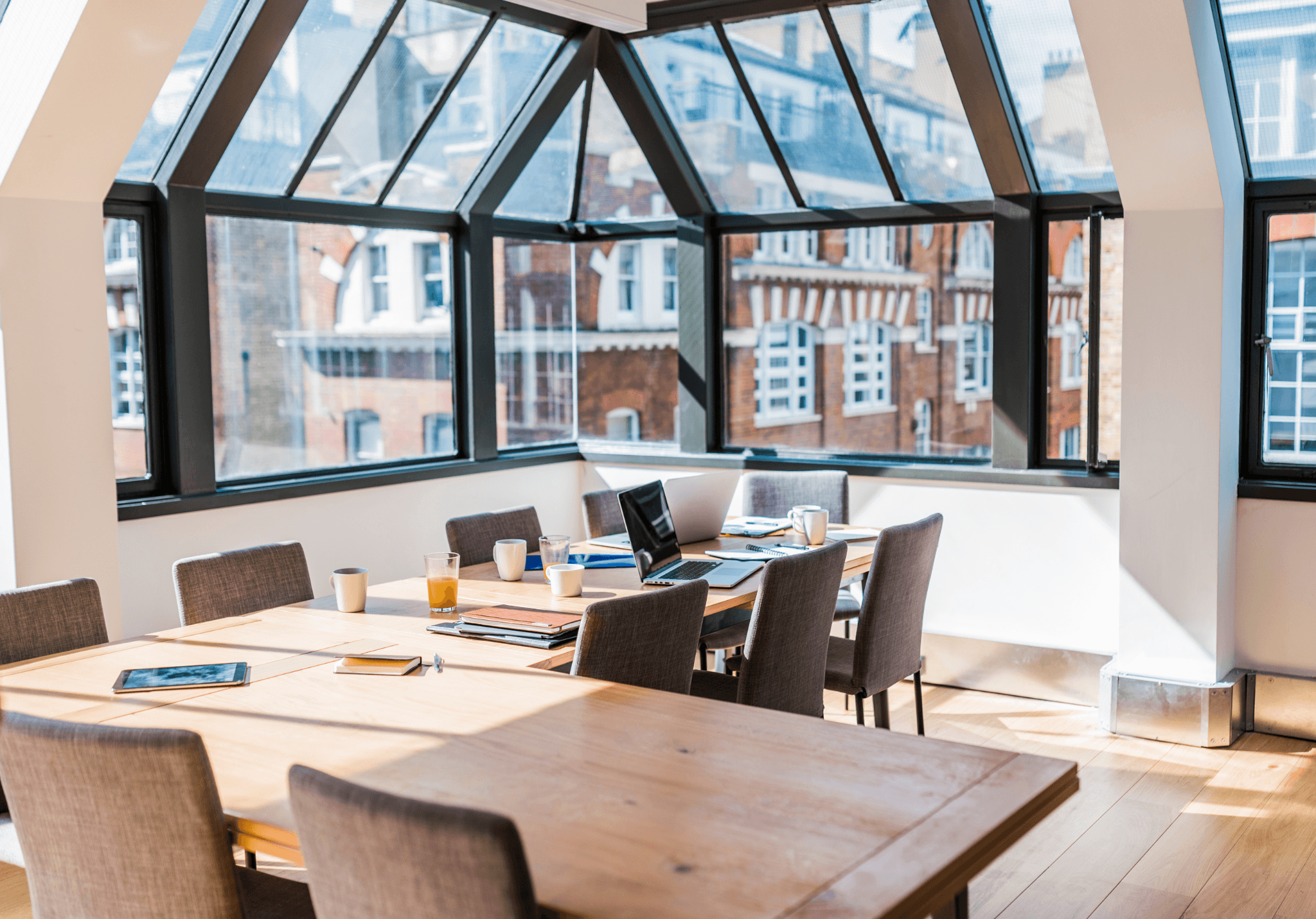 Bright boardroom space with a glass atrium roof and wooden furniture.