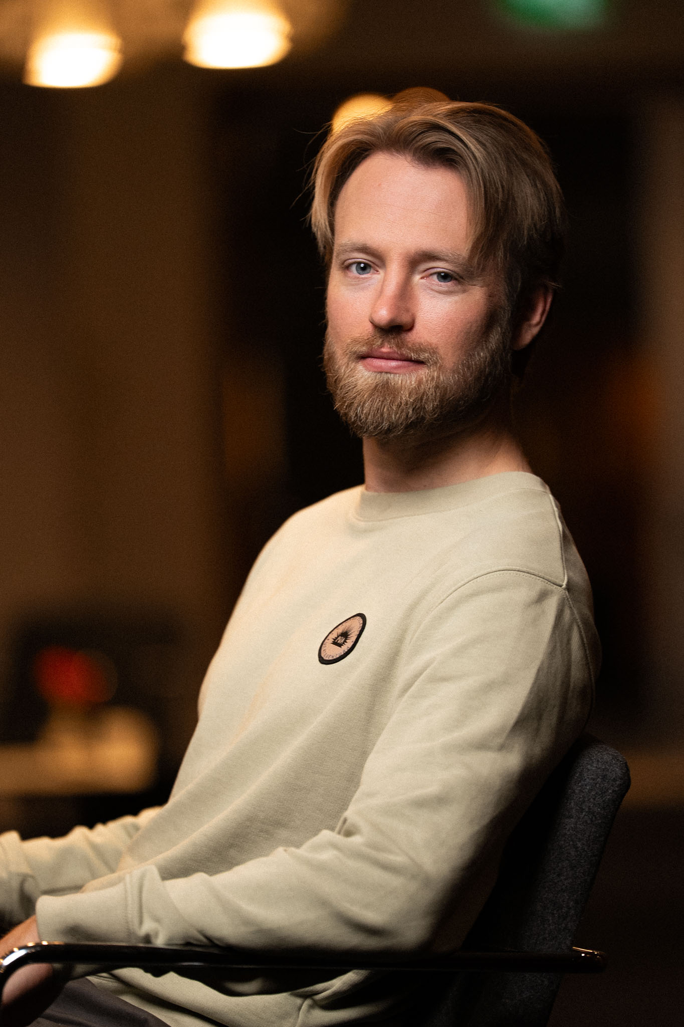 Two soccer players, one in a blue jersey and one in white, sprint side-by-side down a grass field chasing the ball.