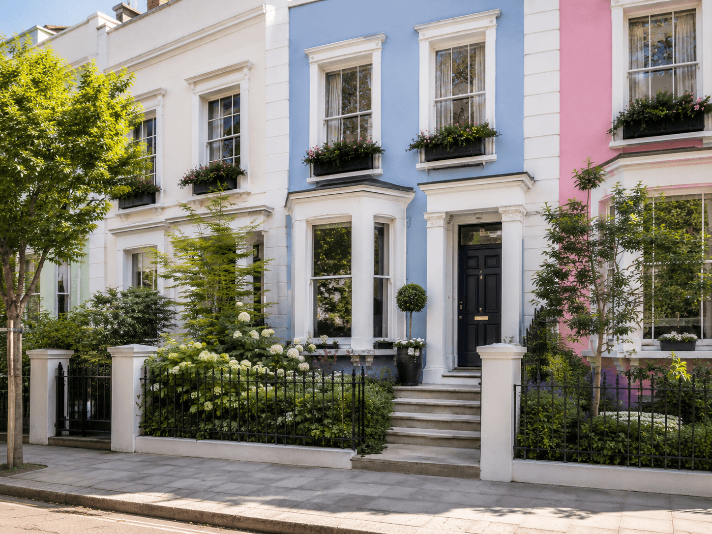 Angled street view of a colorful Notting Hill townhouse with sash windows, flower boxes, black railings, stone steps, and a manicured front garden.