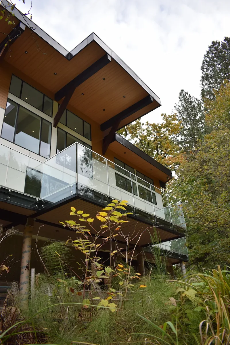 Modern house balcony glass design with frameless panels and wood soffits on a contemporary multi-level home.
