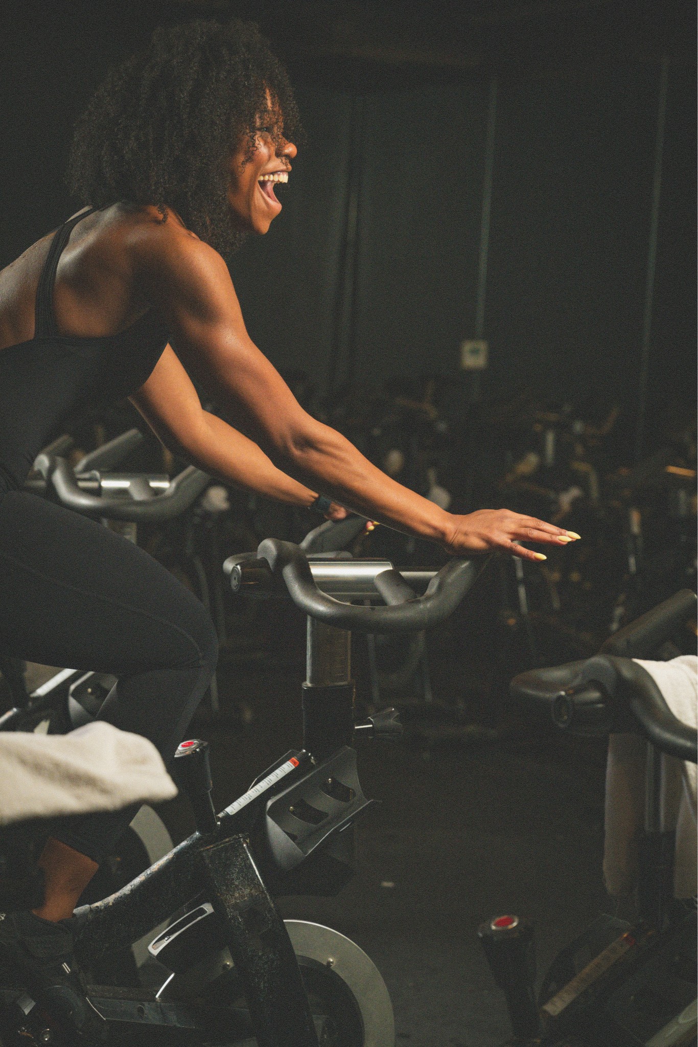 Woman smiling while riding a stationary bike in a group cycling class