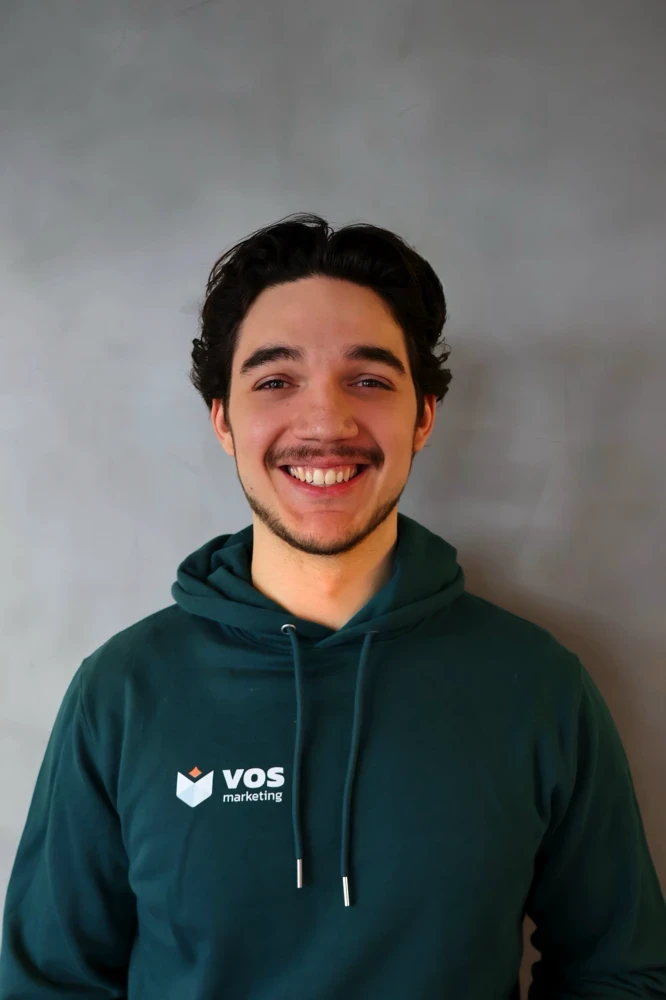 Marnix Vos, oprichter van Vos Marketing, lachend in donkergroene hoodie met logo
