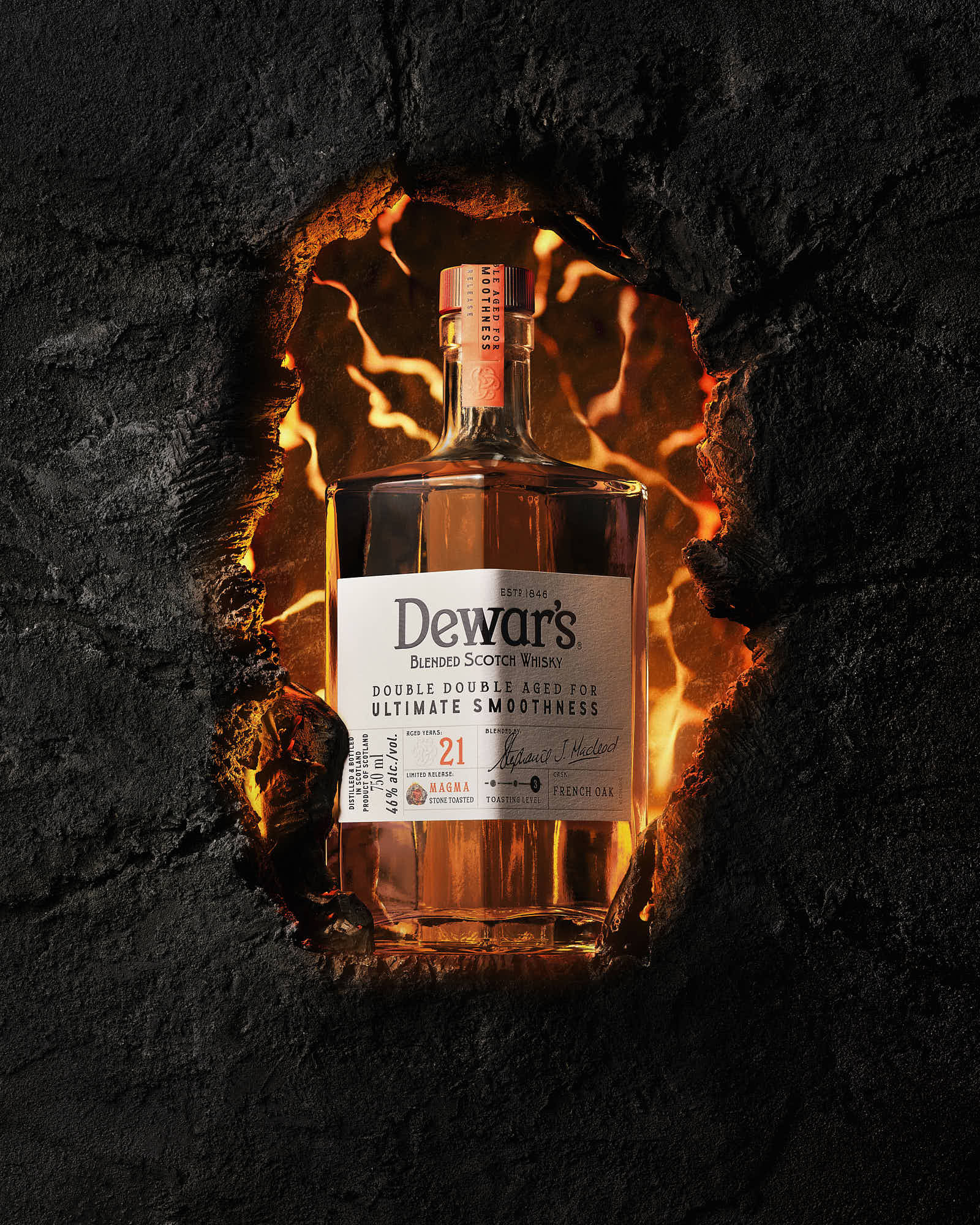 A close-up of an amber bottle with a white label, resting on a dark textured surface.