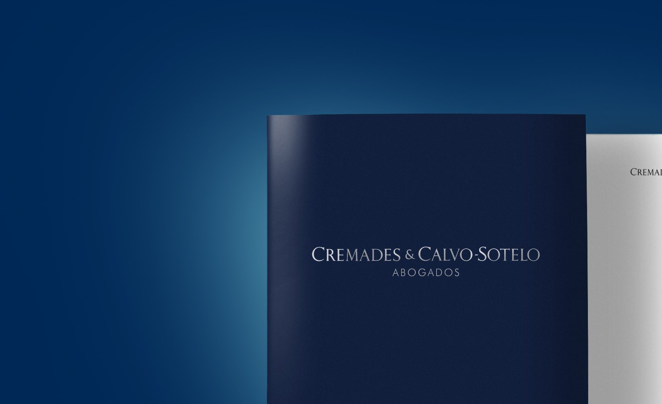 Dark blue folder with "Cremades & Calvo-Sotelo Abogados" in elegant white letters, set against a gradient blue background. Professional and sophisticated tone.