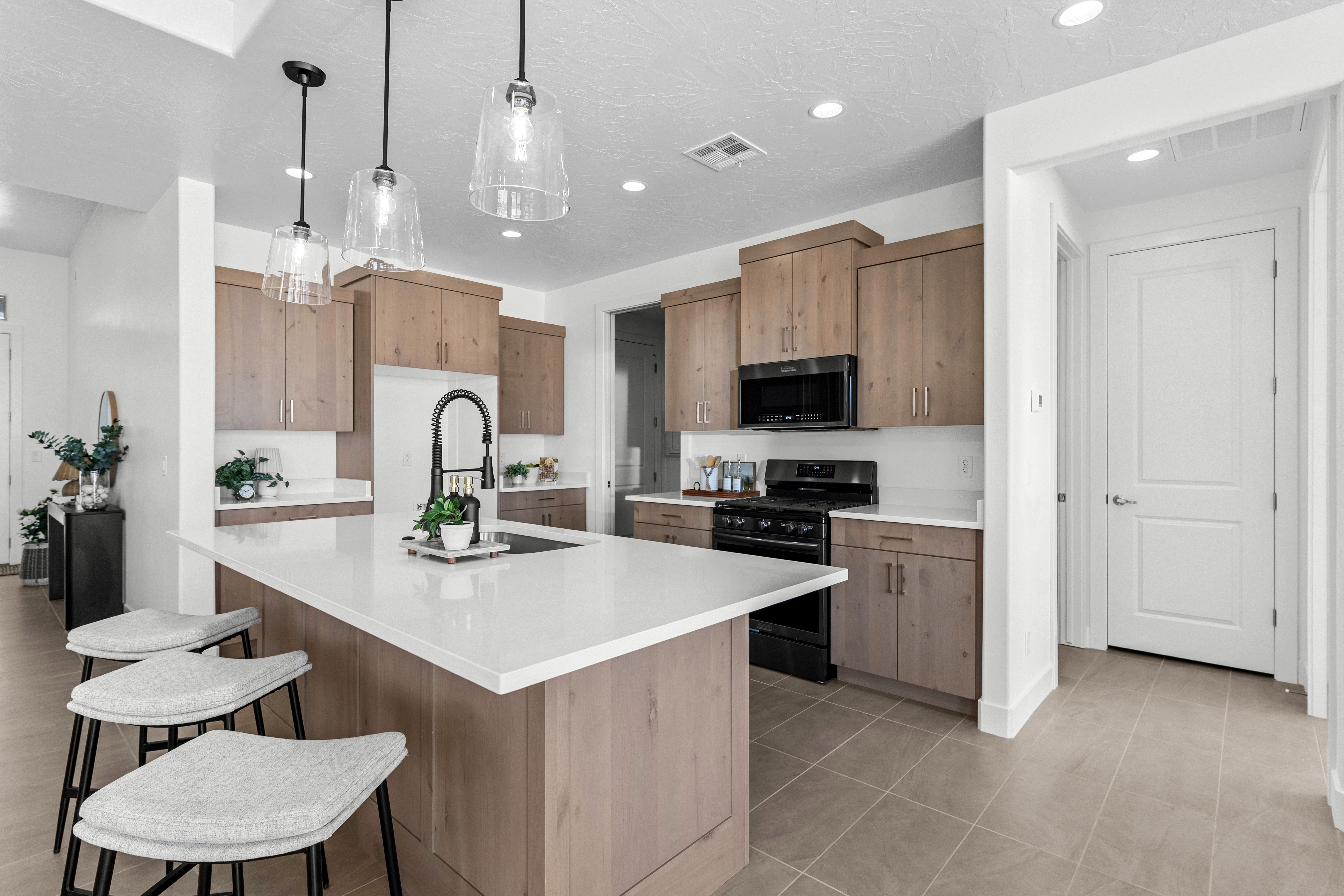 Kitchen of The Nest at Falcon Ridge in Hurricane, Utah, featuring a large island and wood cabinetry with white countertops.
