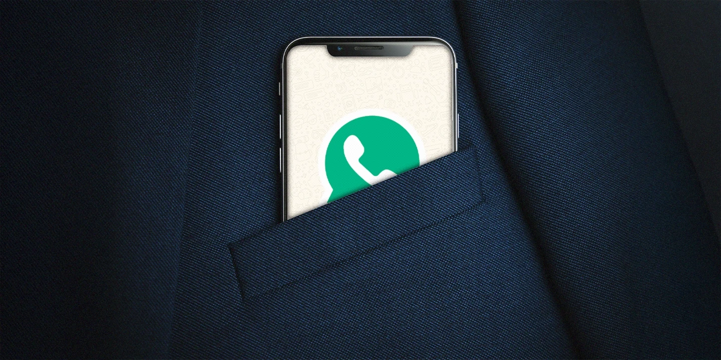 Celular parcialmente visível no bolso de um terno escuro, exibindo a tela do WhatsApp