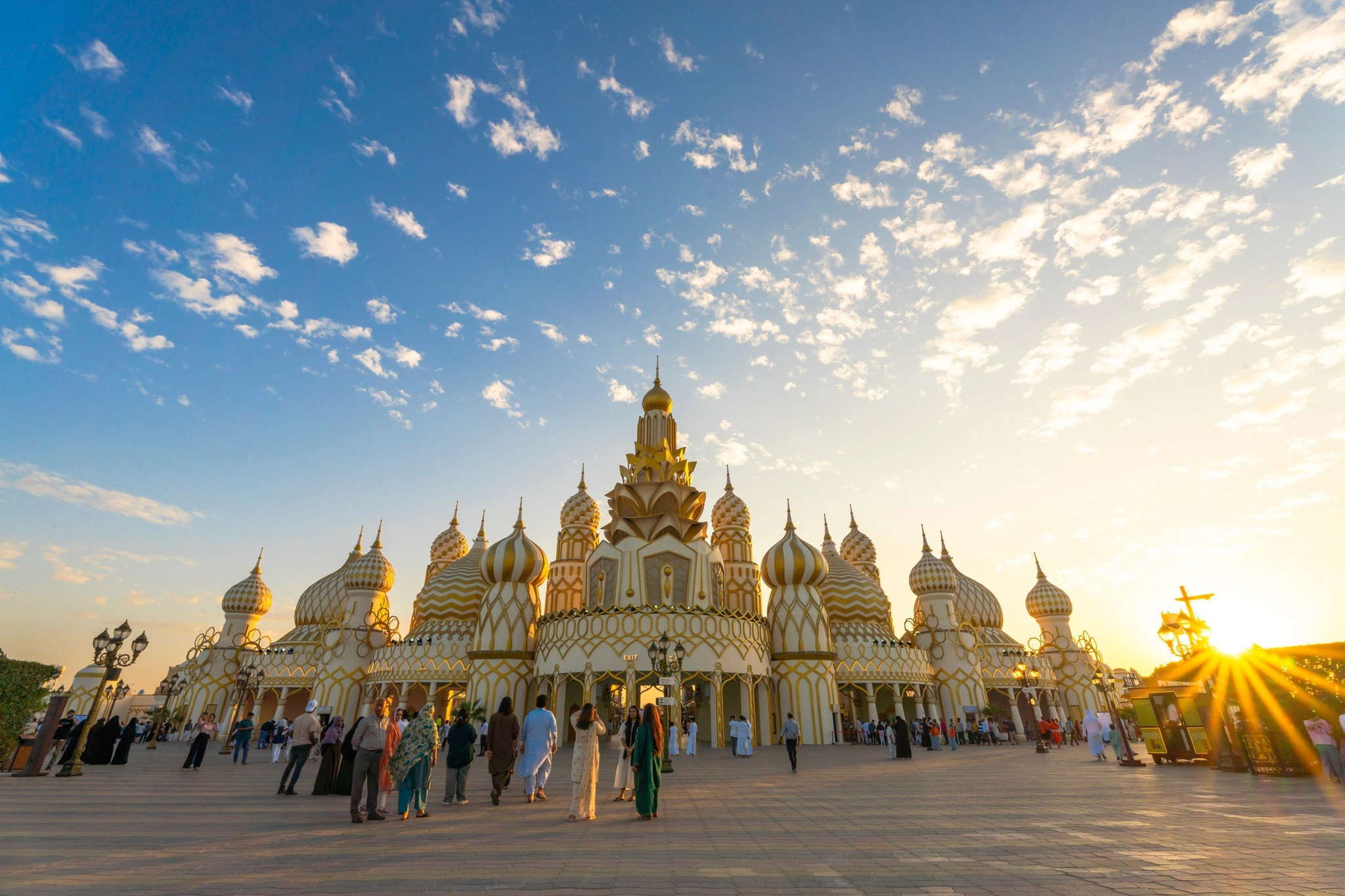 The Global Village entrance with golden domes at sunset and guests approaching.&nbsp;