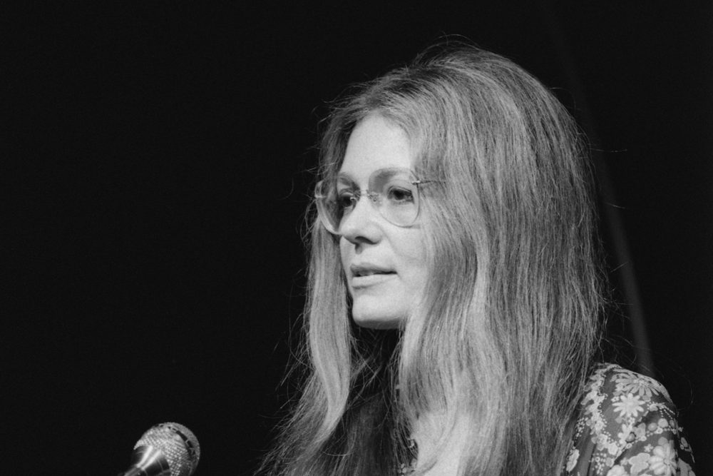 Gloria Steinem speaking at a microphone in 1975