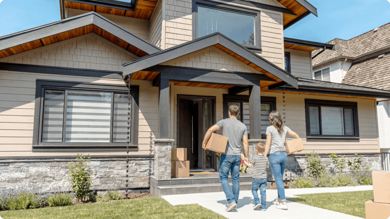Family carrying boxes into their completed custom home after moving in