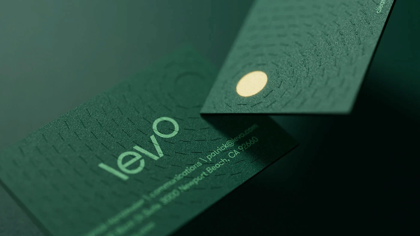 Two smiling models in close-up portrait, one with dark curly hair and burgundy lipstick, one with dark bangs and freckles, wearing black turtlenecks