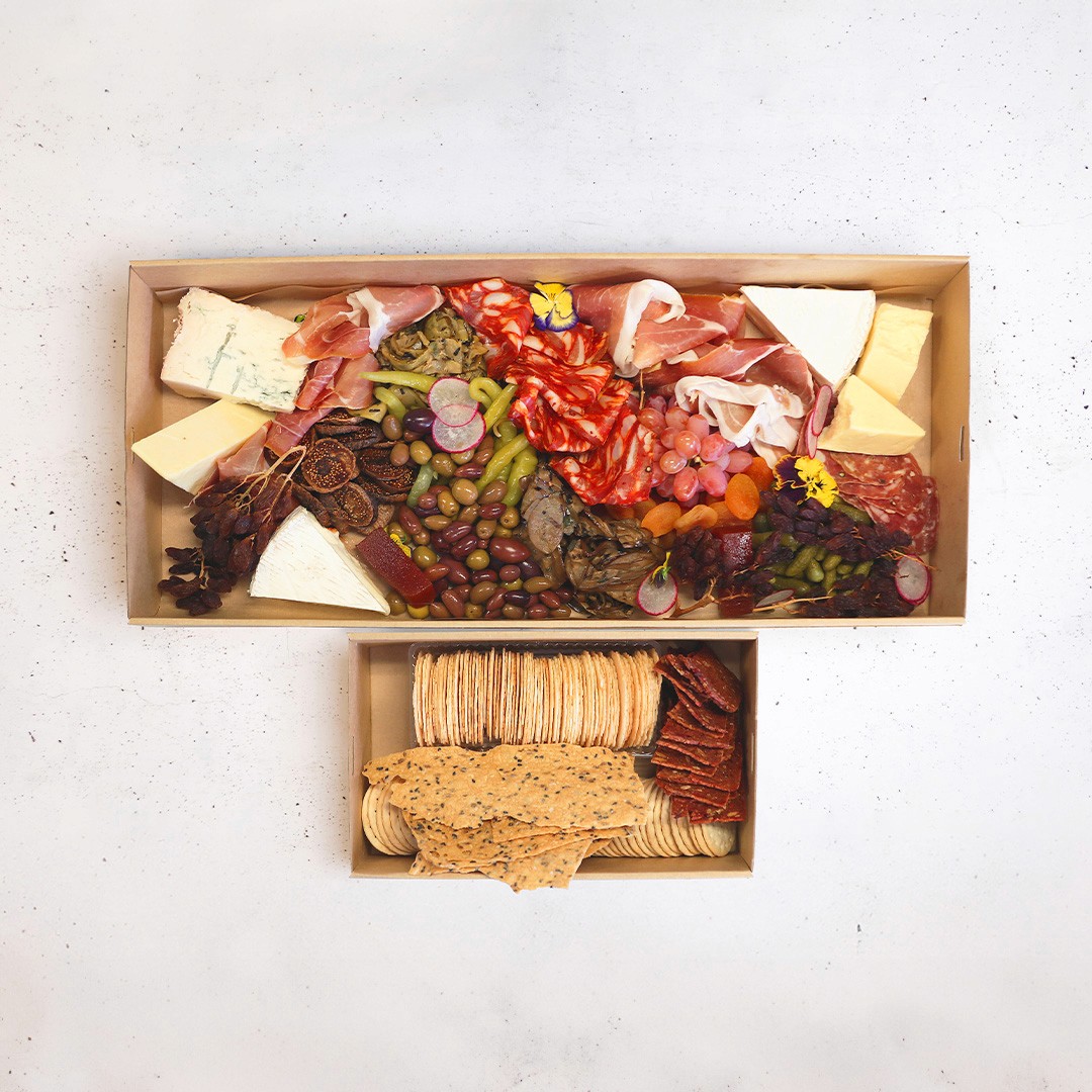 Boxed grazing platter with sliced meats, cheese, vegtables and crackers