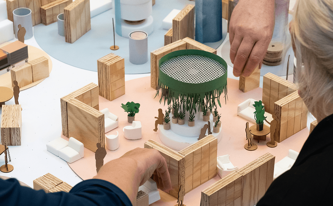 Modell des modularen micasa Experience Stores aus Holz, Schaum und Papier, an dem drei Personen arbeiten und verschiedene Elemente verschieben, um Shopkonfigurationen zu testen.