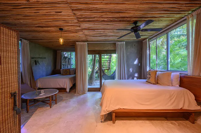 Oceanfront Room at Nômade Tulum featuring outdoor seating area with cabana-style shade, direct ocean view, and beautiful palm trees by the sea.